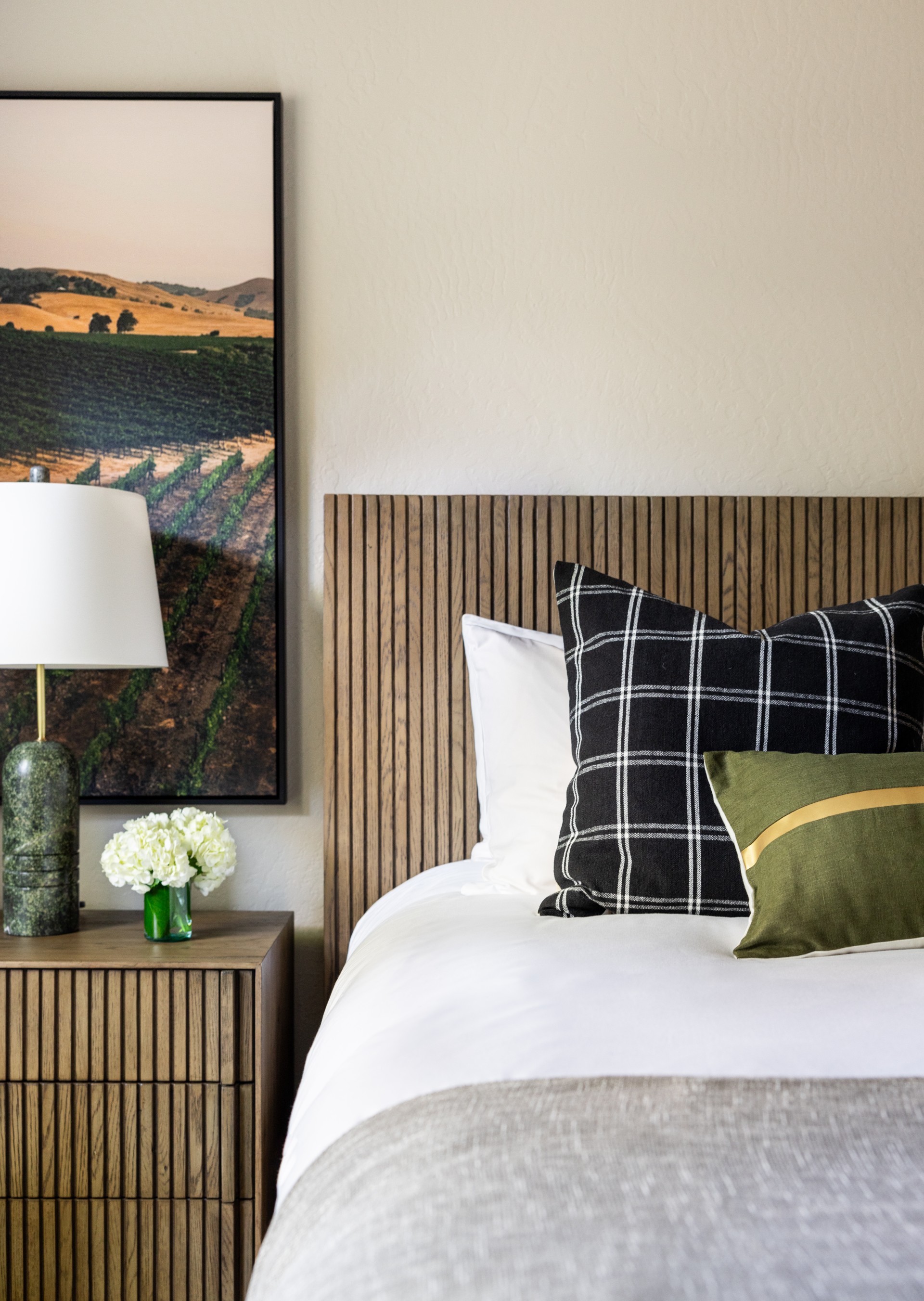 a bed with a lamp and a picture on the wall