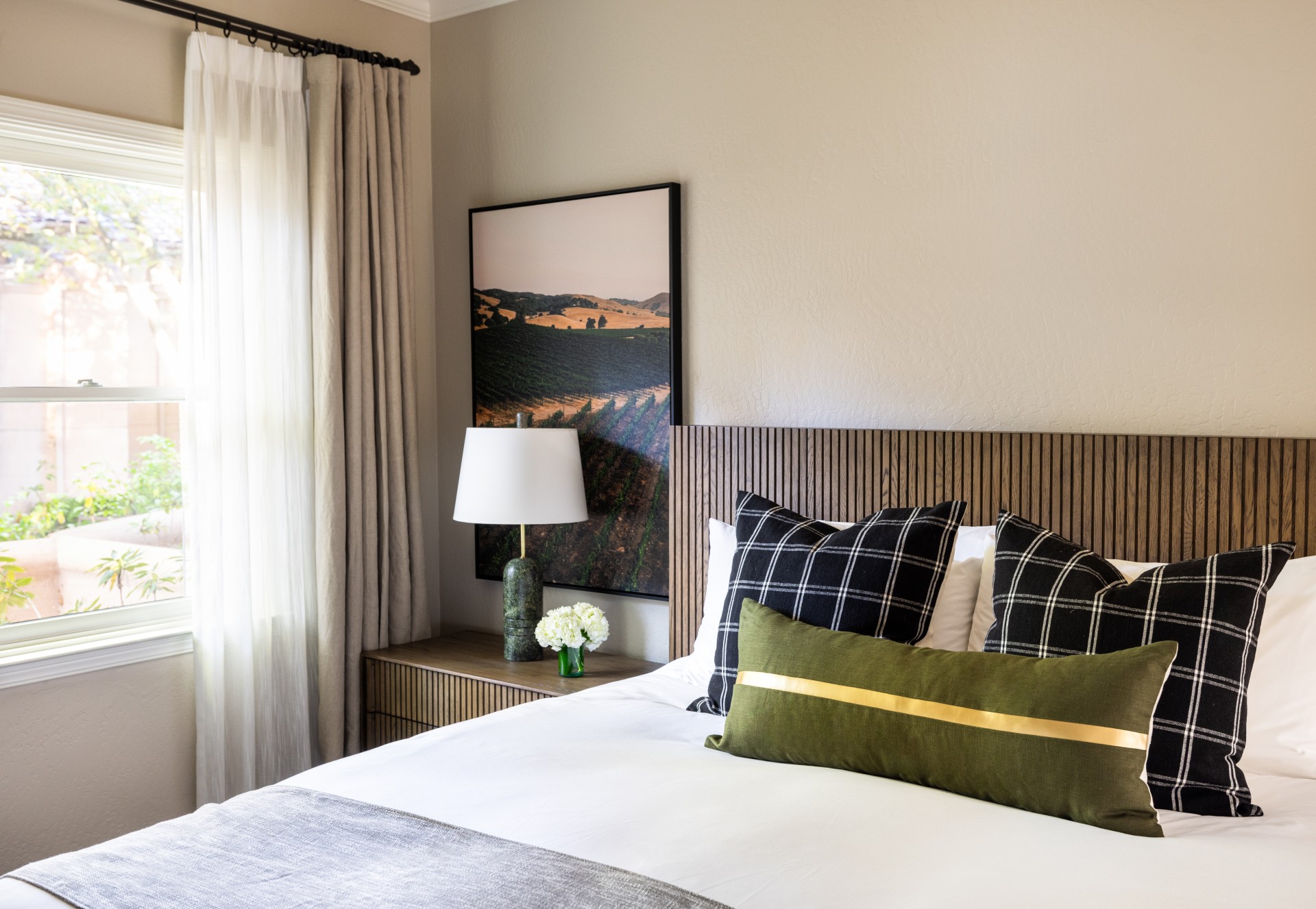a bed with pillows and a lamp next to a window
