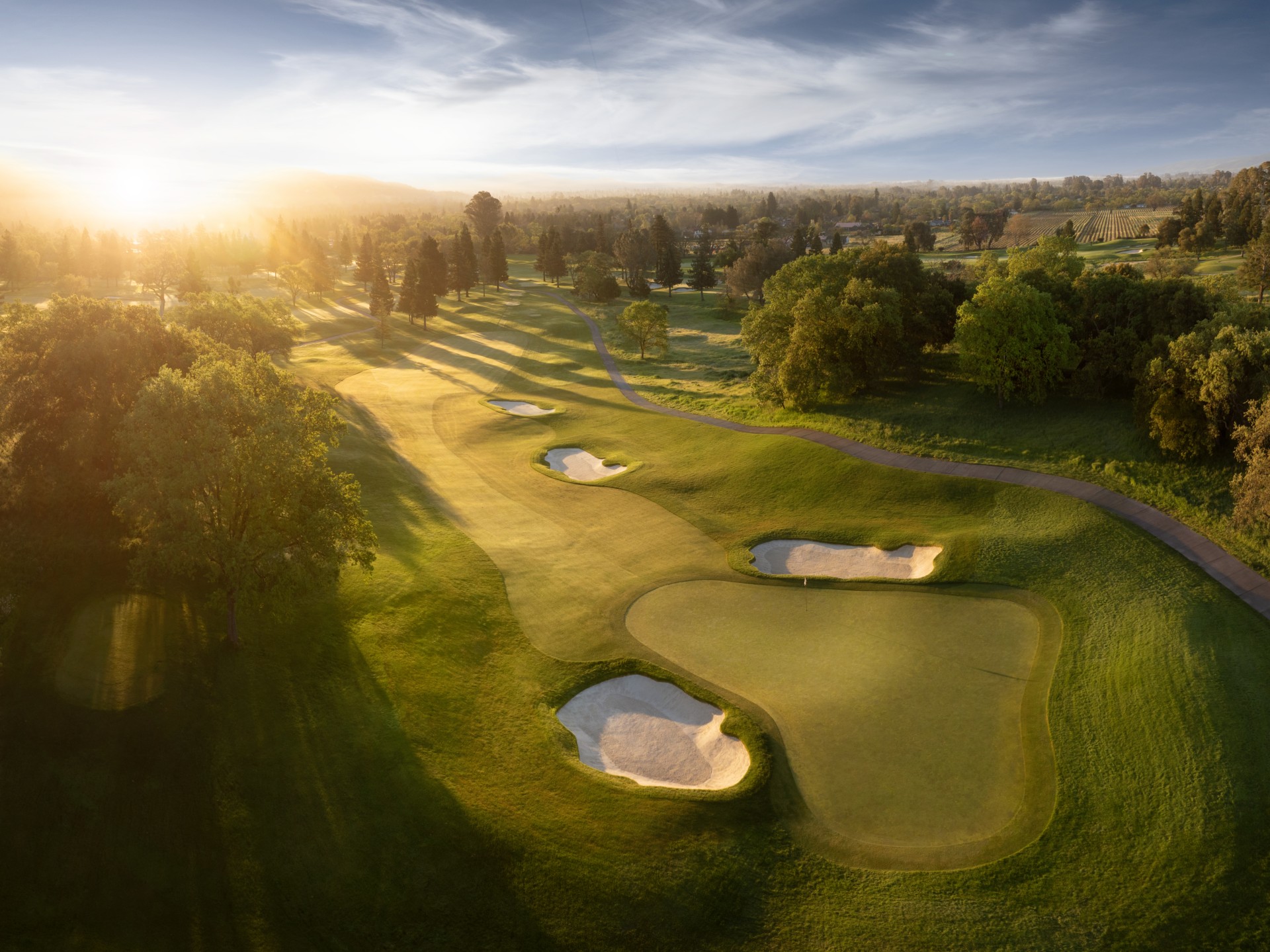 a golf course with sand bunkers and trees