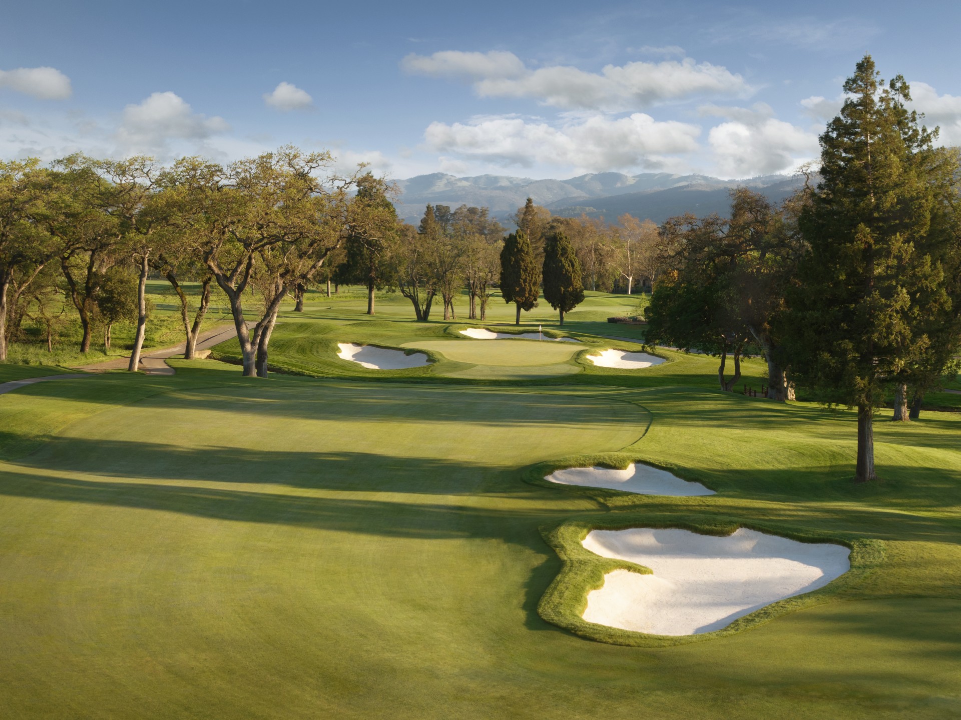 a golf course with sand bunkers and trees