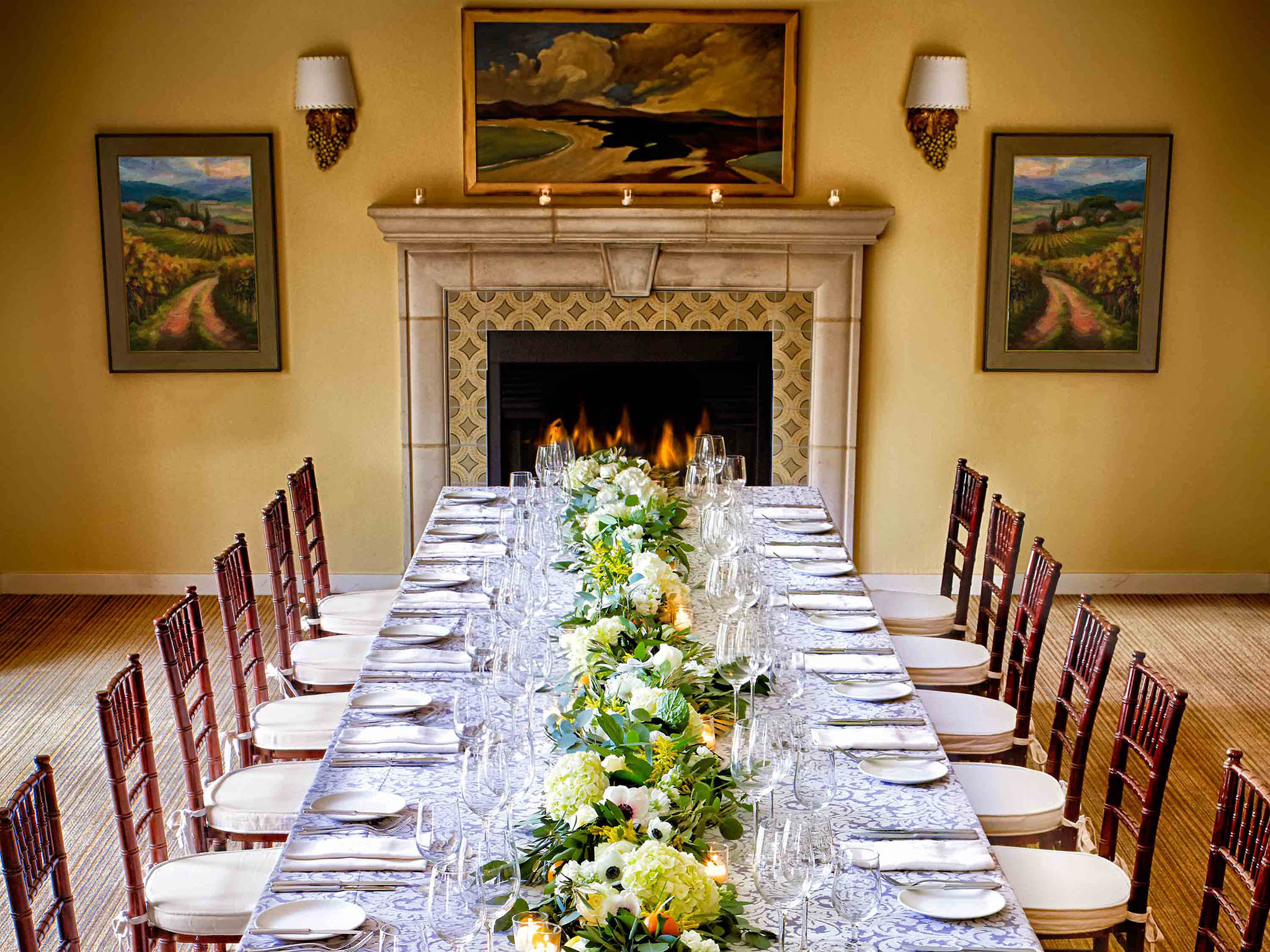 a long table with white chairs and flowers on it