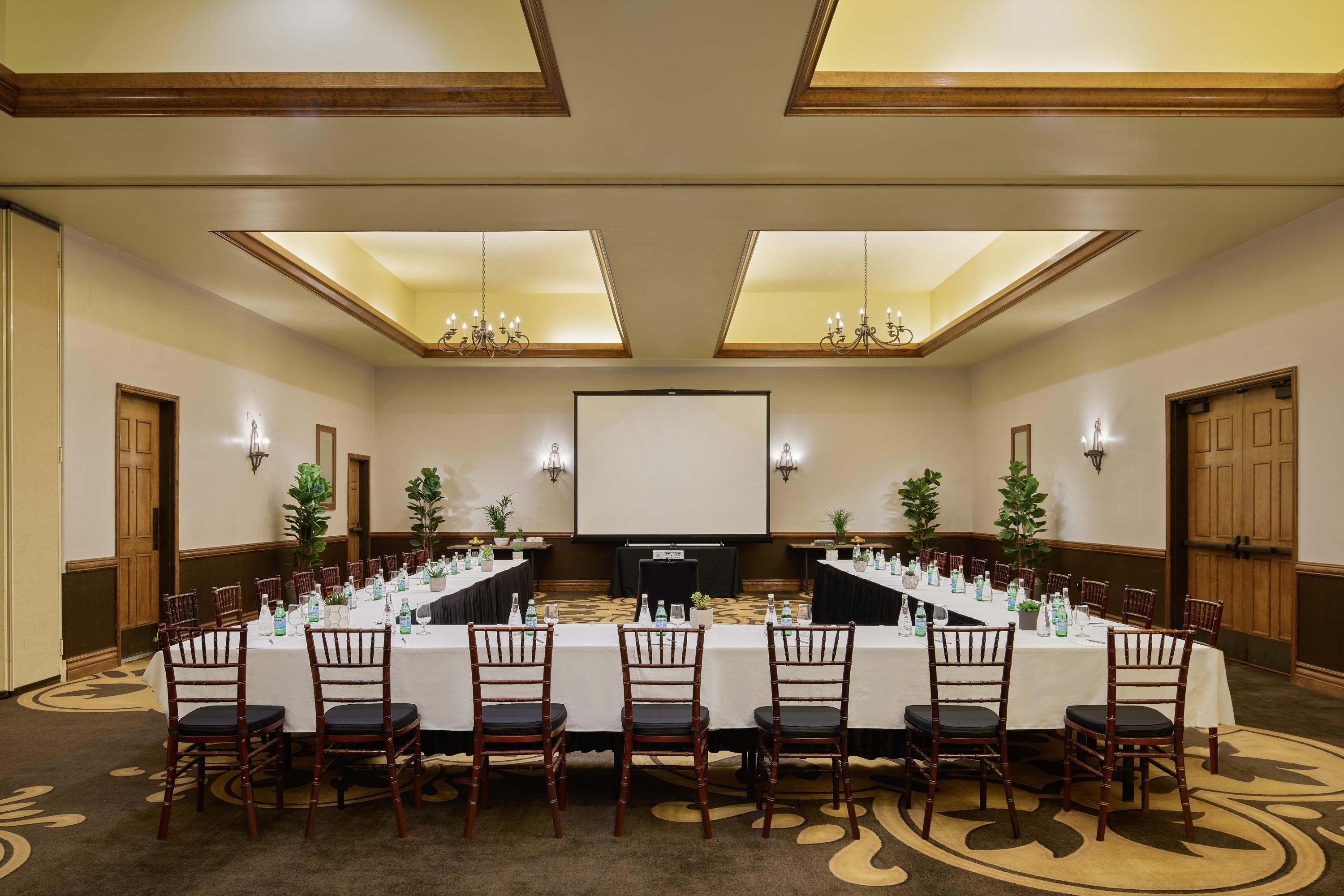 a room with a large table with chairs and a projector screen