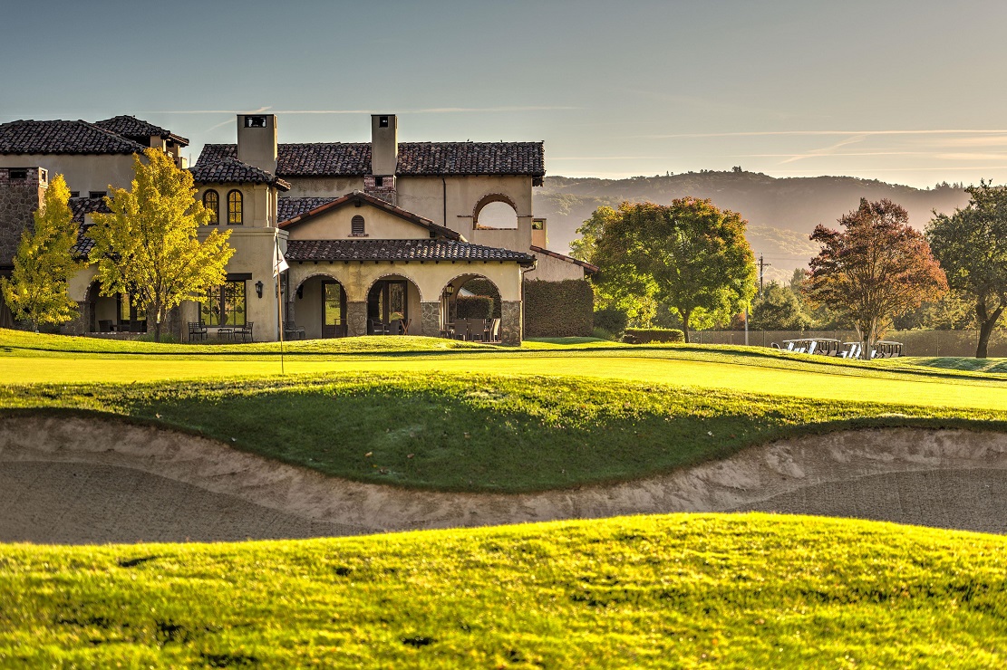 a golf course with a house and a sand trap