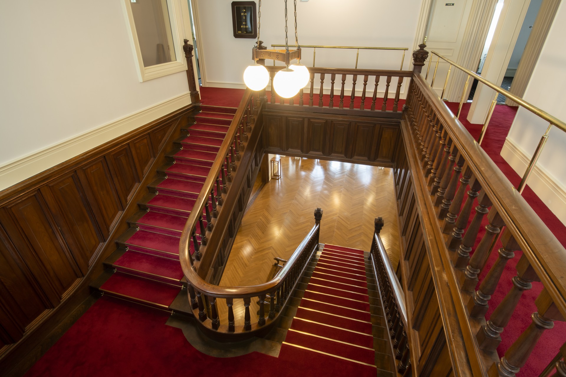 a staircase with red carpet and wood railings