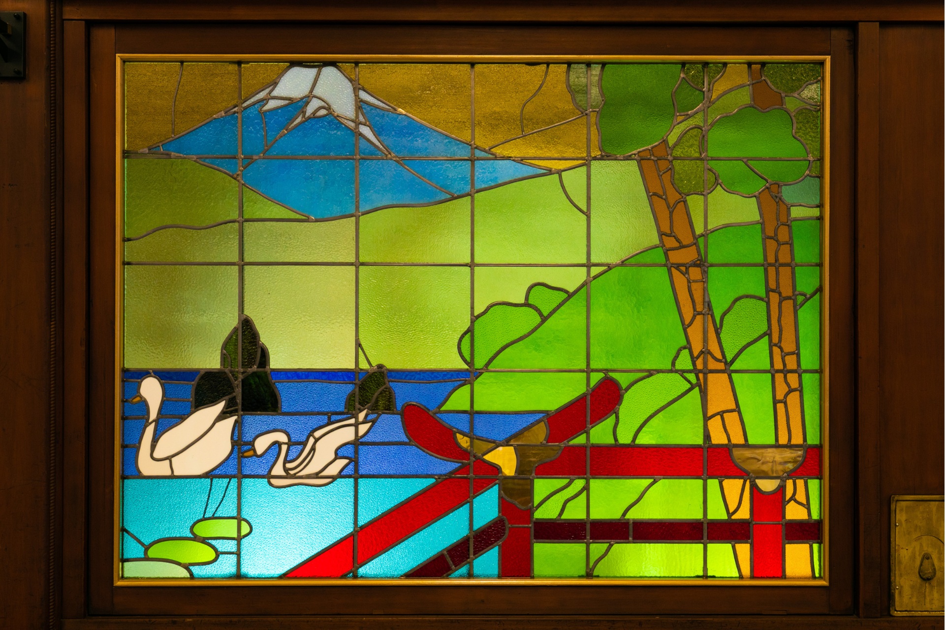 a stained glass window with a mountain and trees
