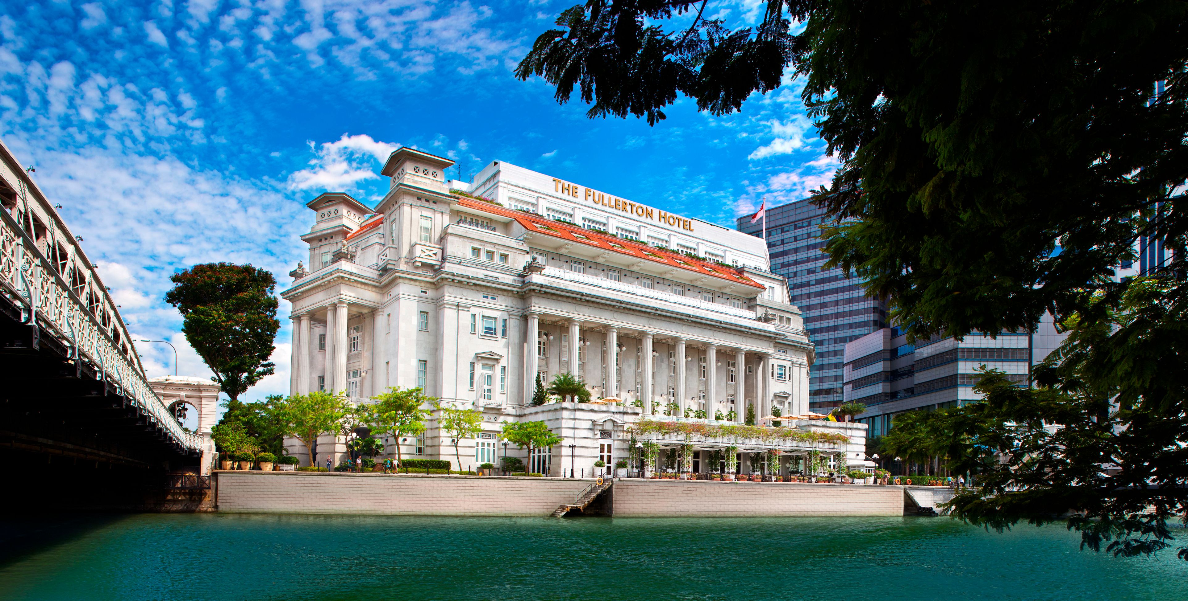 a large white building with columns and a red roof with The Fullerton Hotel Singapore in the background