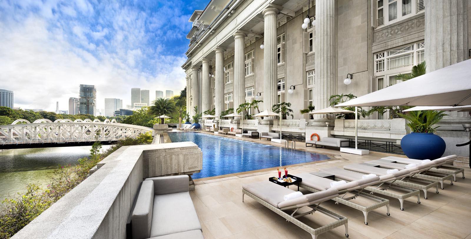 a pool with lounge chairs and a large building with columns