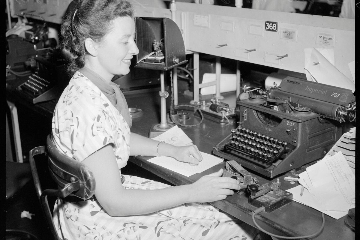 a woman sitting at a desk using a typewriter