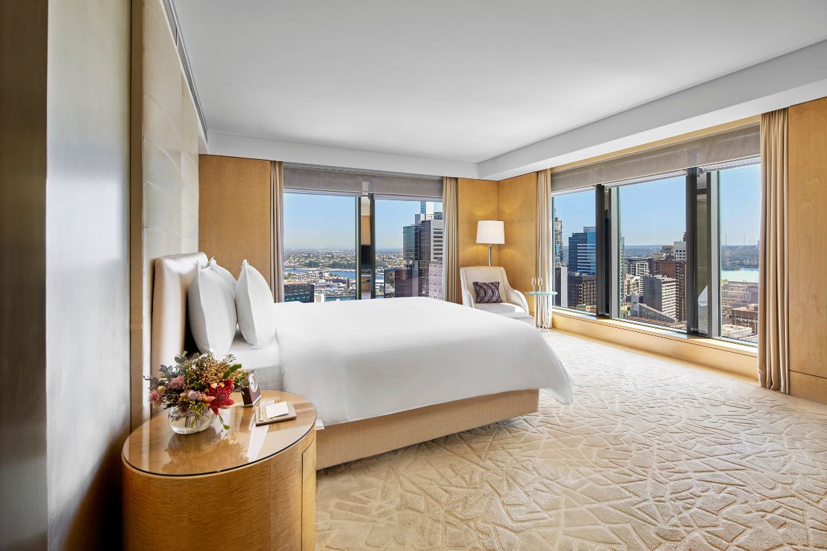 a bedroom with a large bed and a table with a city view