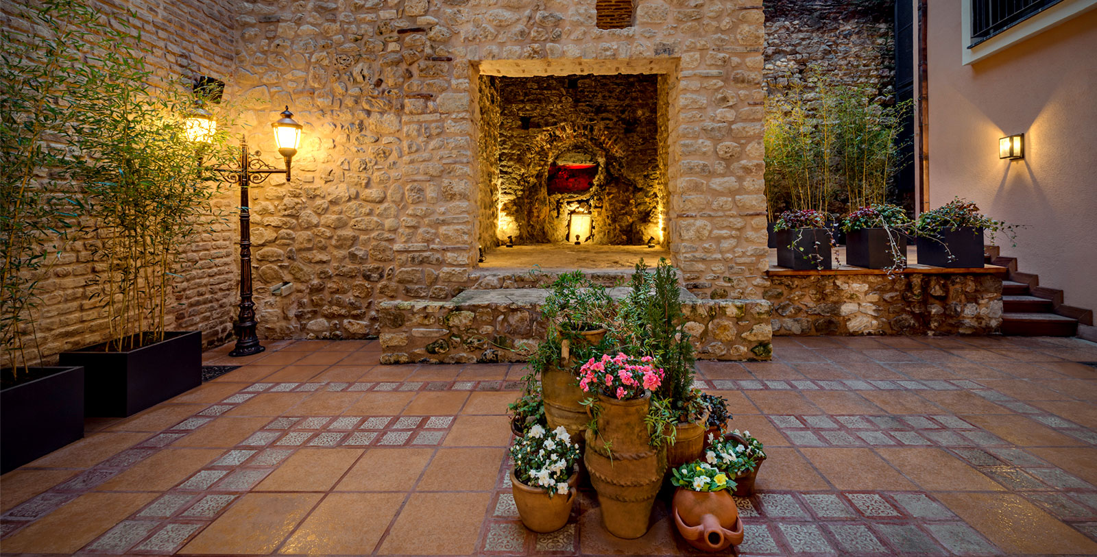 a stone building with plants and lights