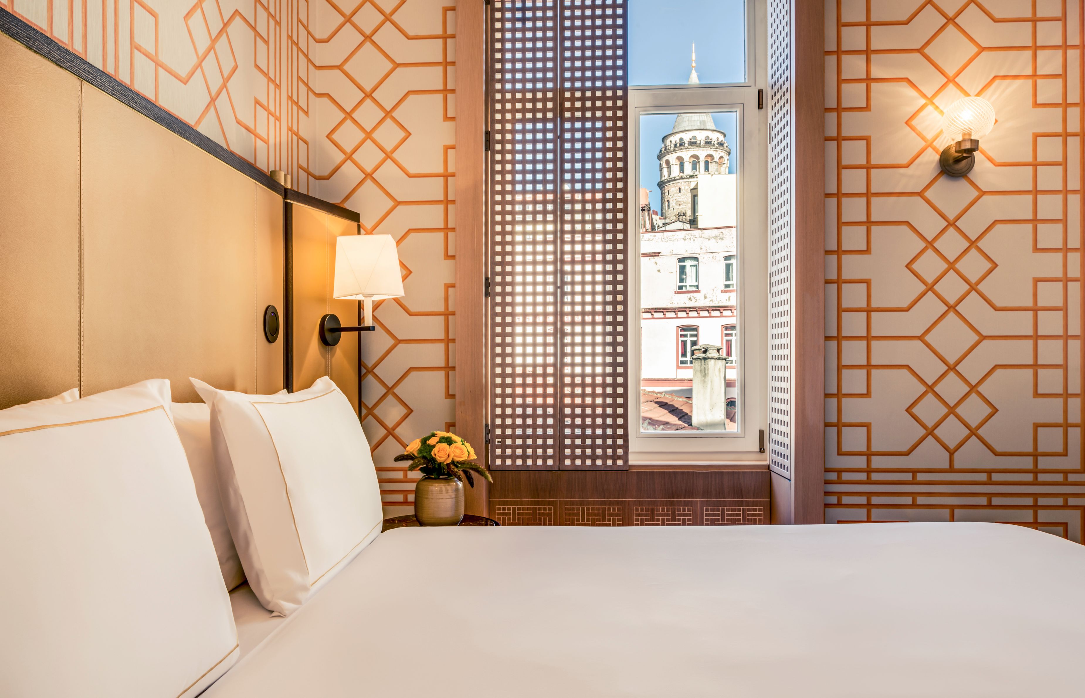 a bed with a vase of flowers and a window