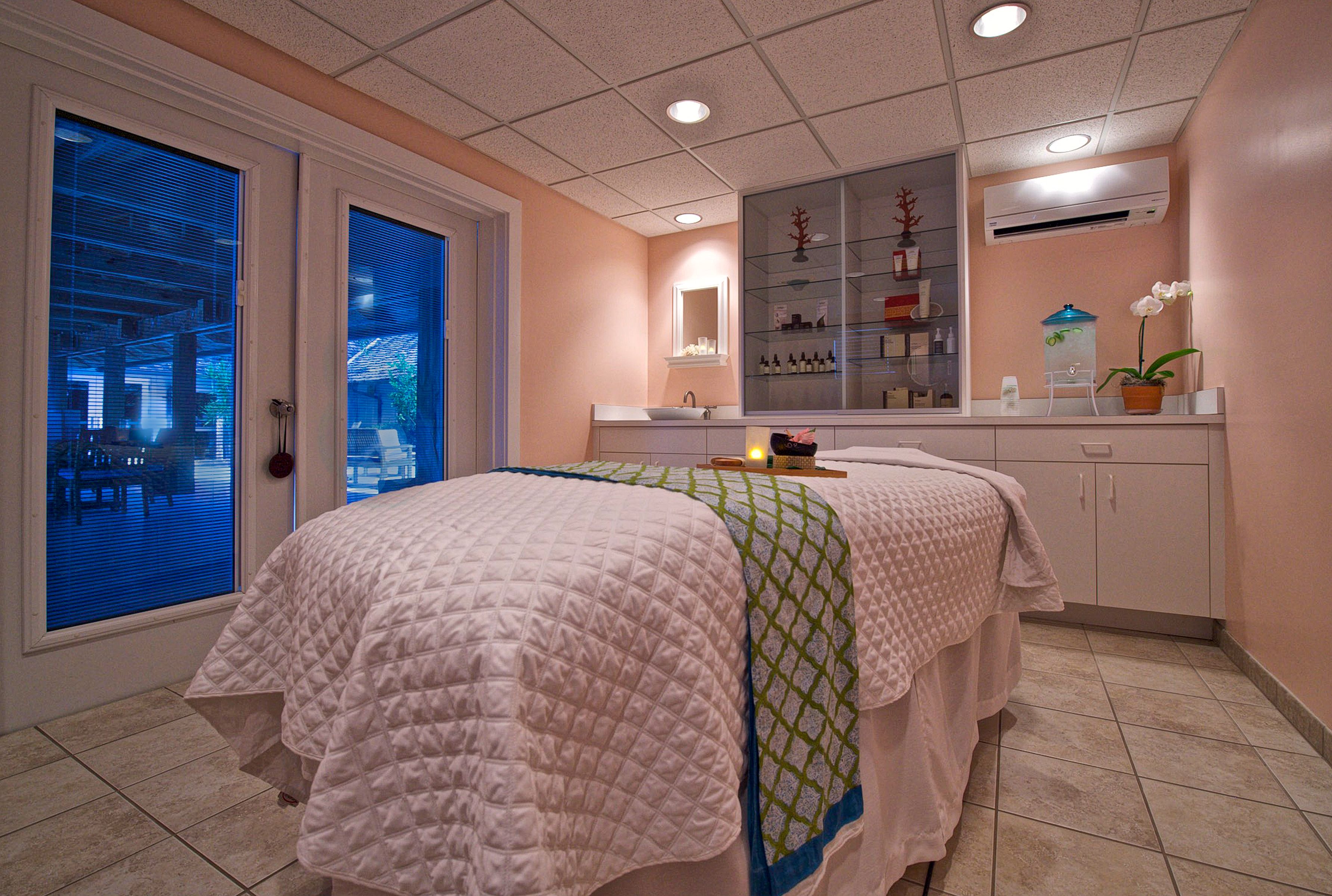 a massage room with a bed and a glass door