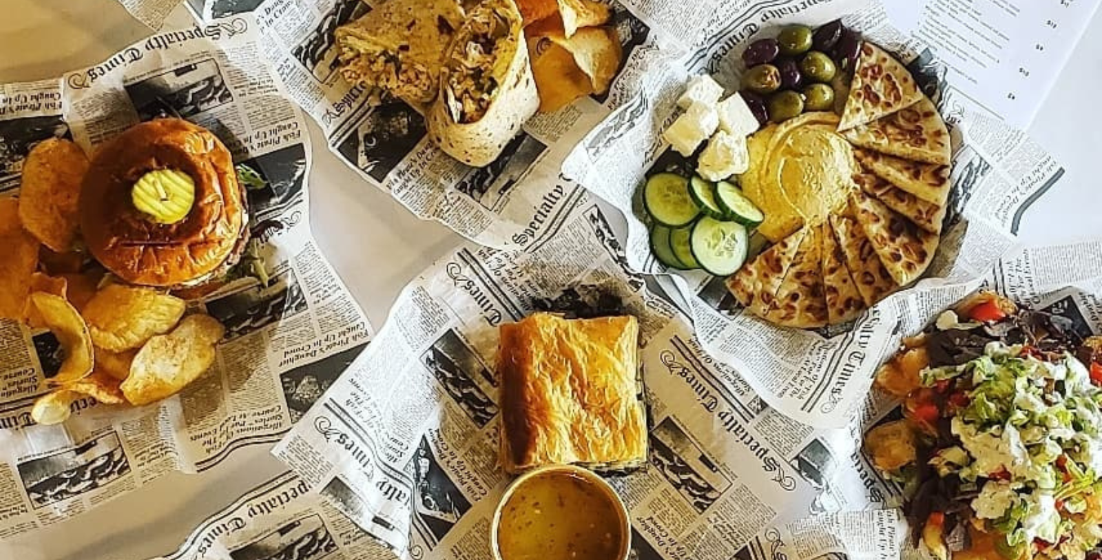 food on newspaper with a cup of sauce