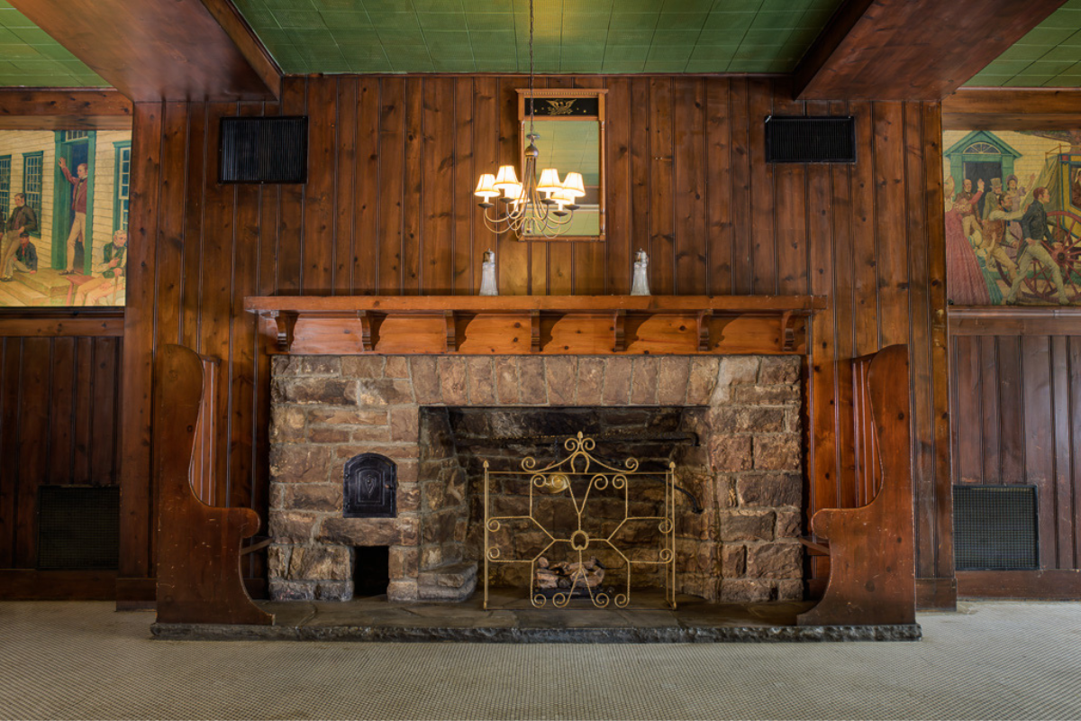 a fireplace with a chandelier and wood paneling