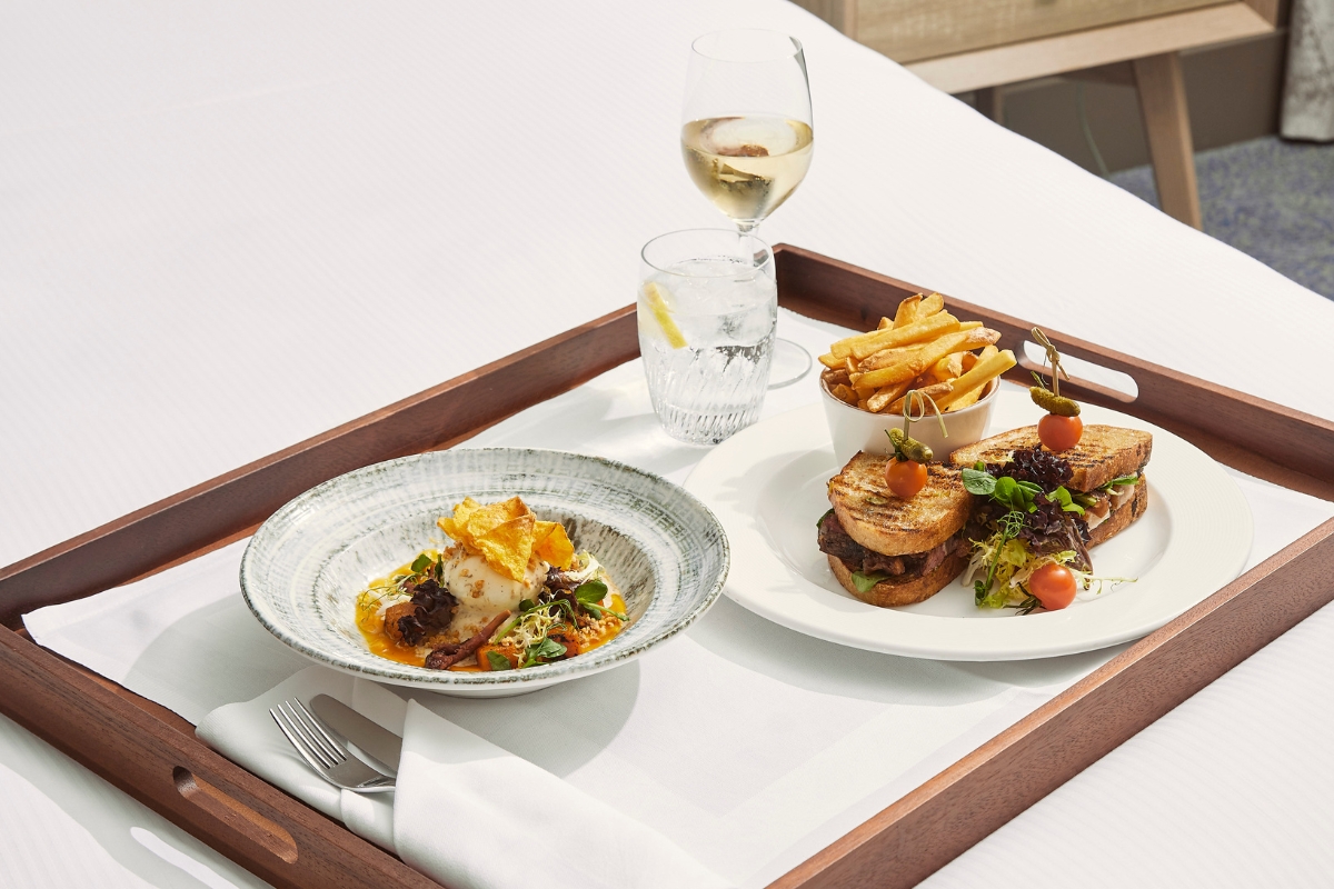 a tray with plates of food and a glass of wine