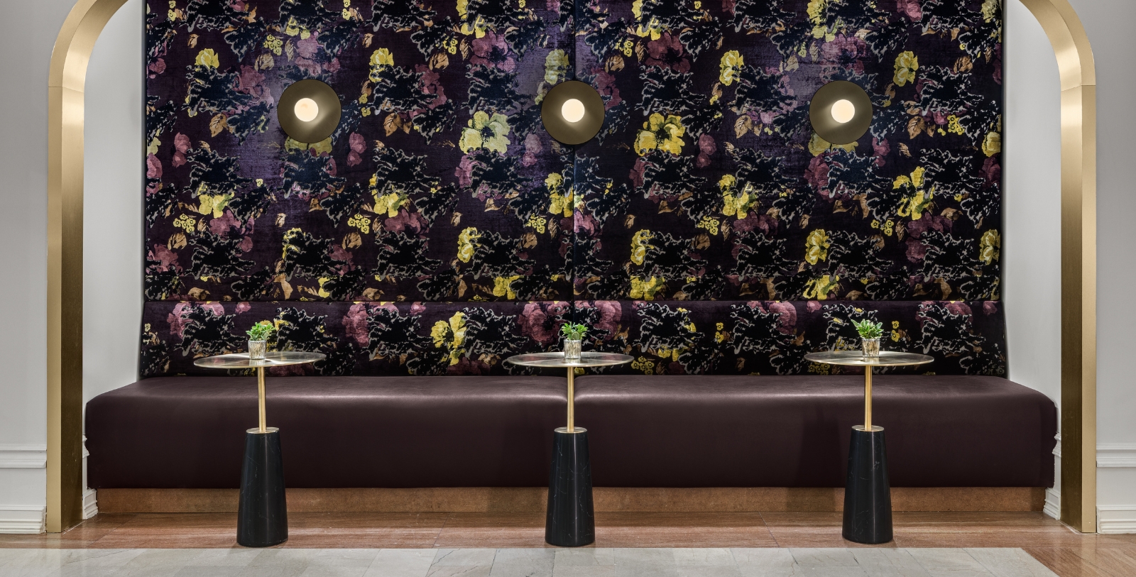 a long bench with tables and chairs in front of a wall with lights