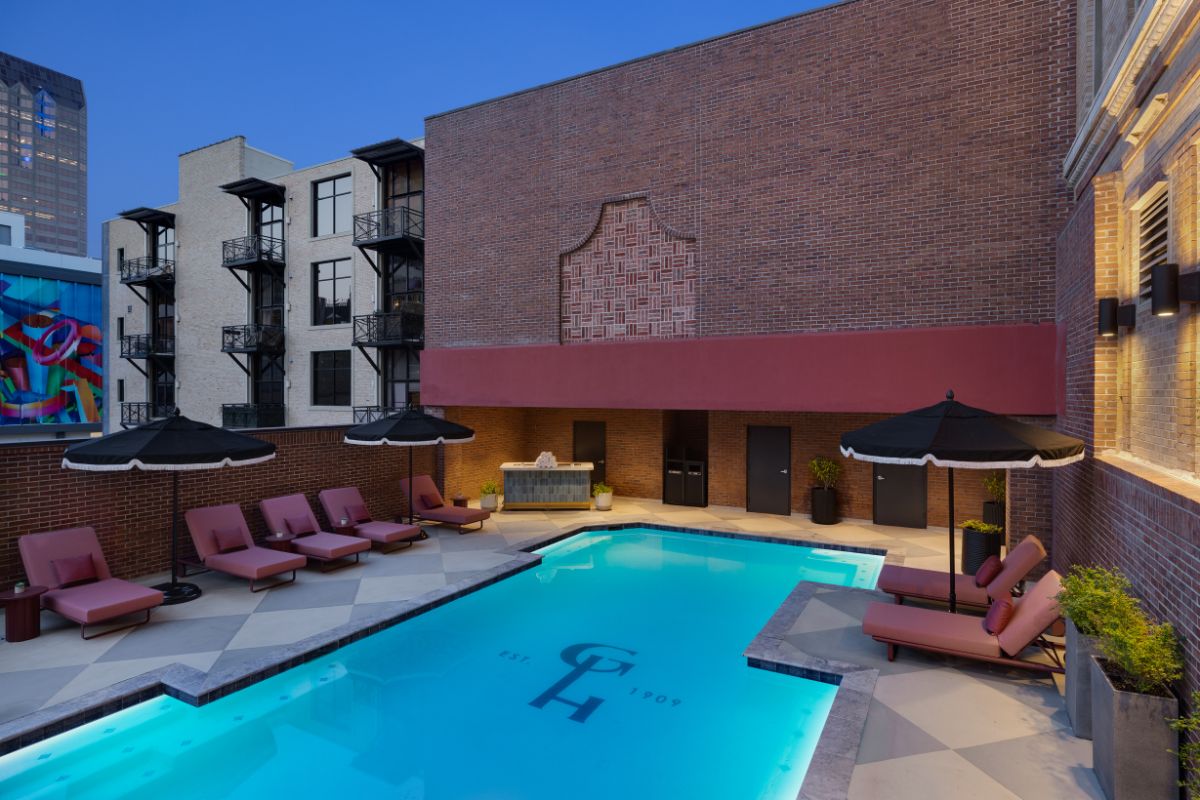 a pool with chairs and umbrellas in front of a building