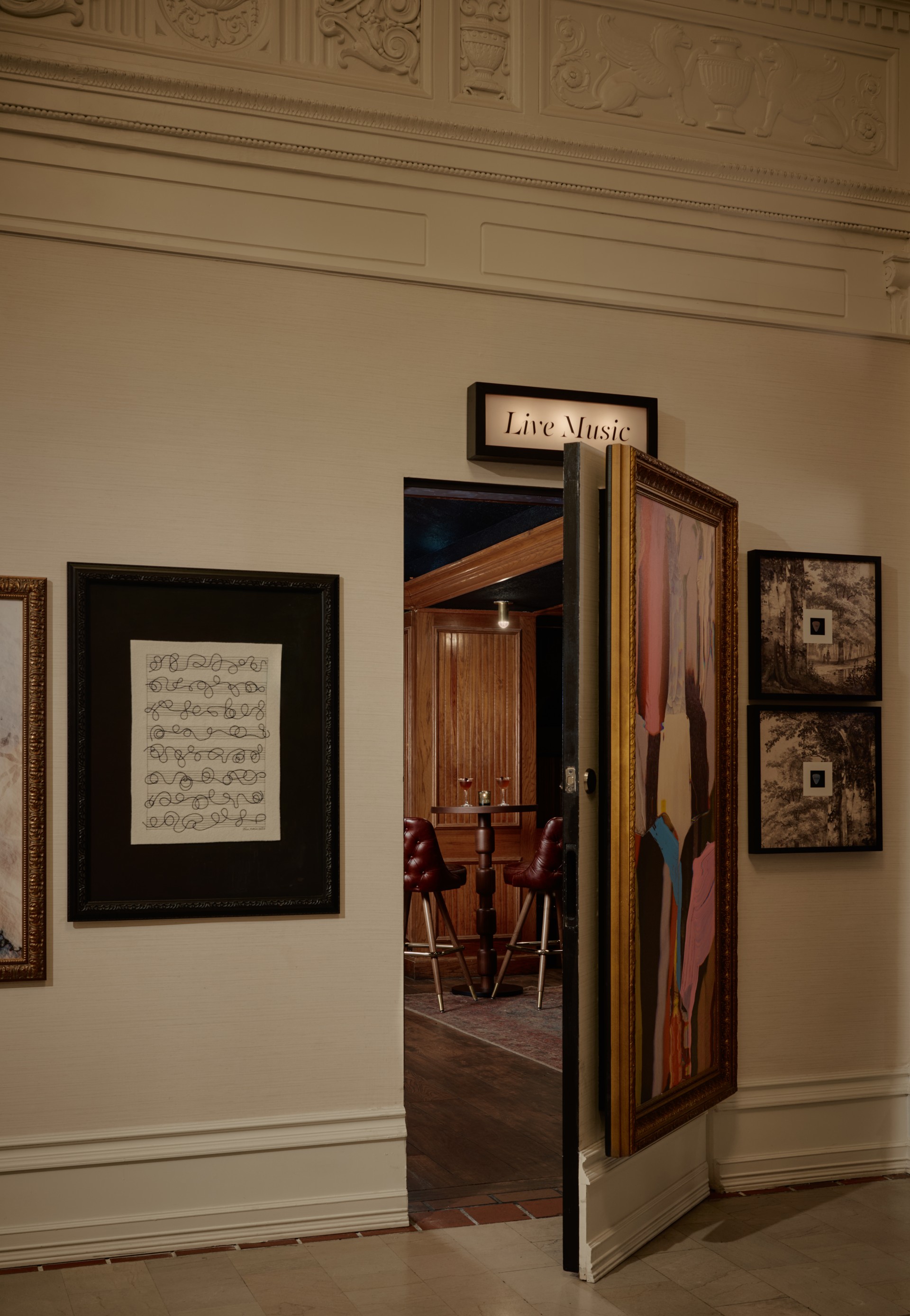 a room with a door open and framed pictures