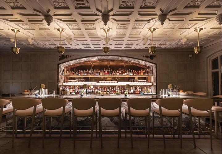 a bar with a row of chairs and a bar with bottles on the counter