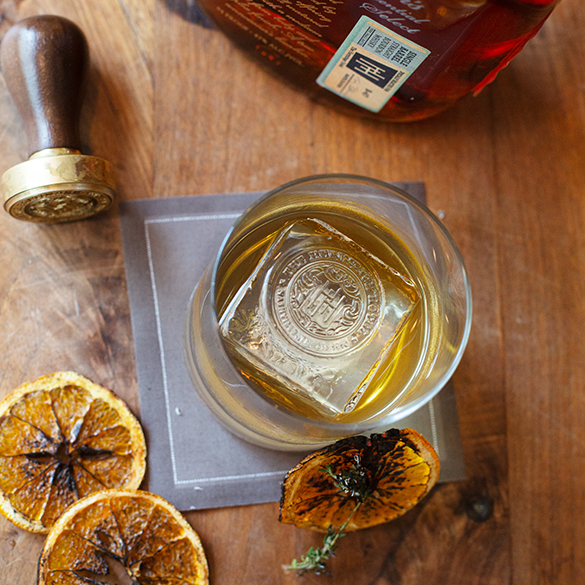 a glass of alcohol with a drink and orange slices on a wood surface