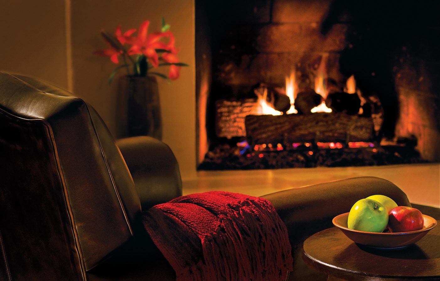 a fireplace with a red blanket and fruit on a couch