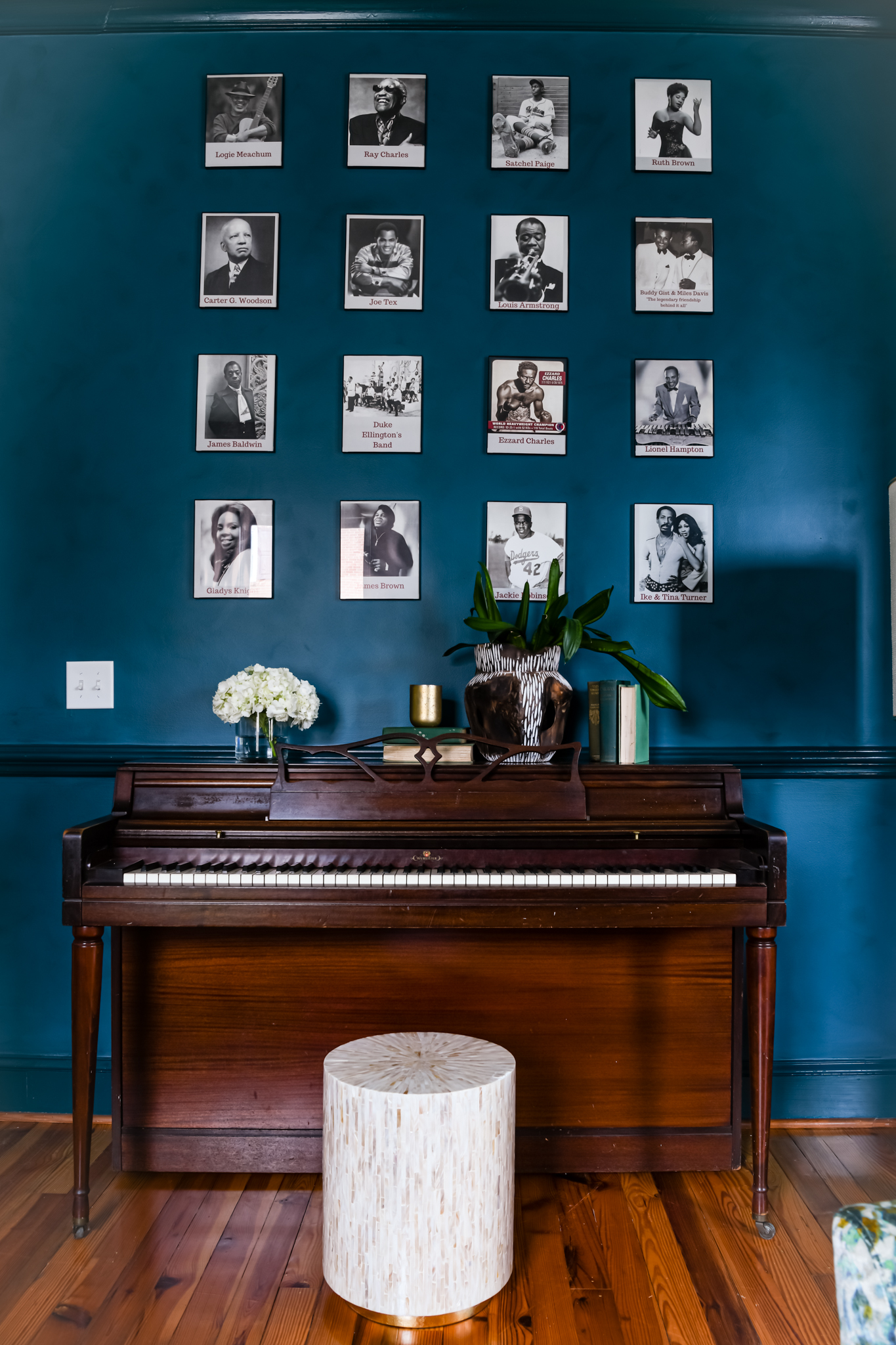 a piano with a stool and pictures on the wall