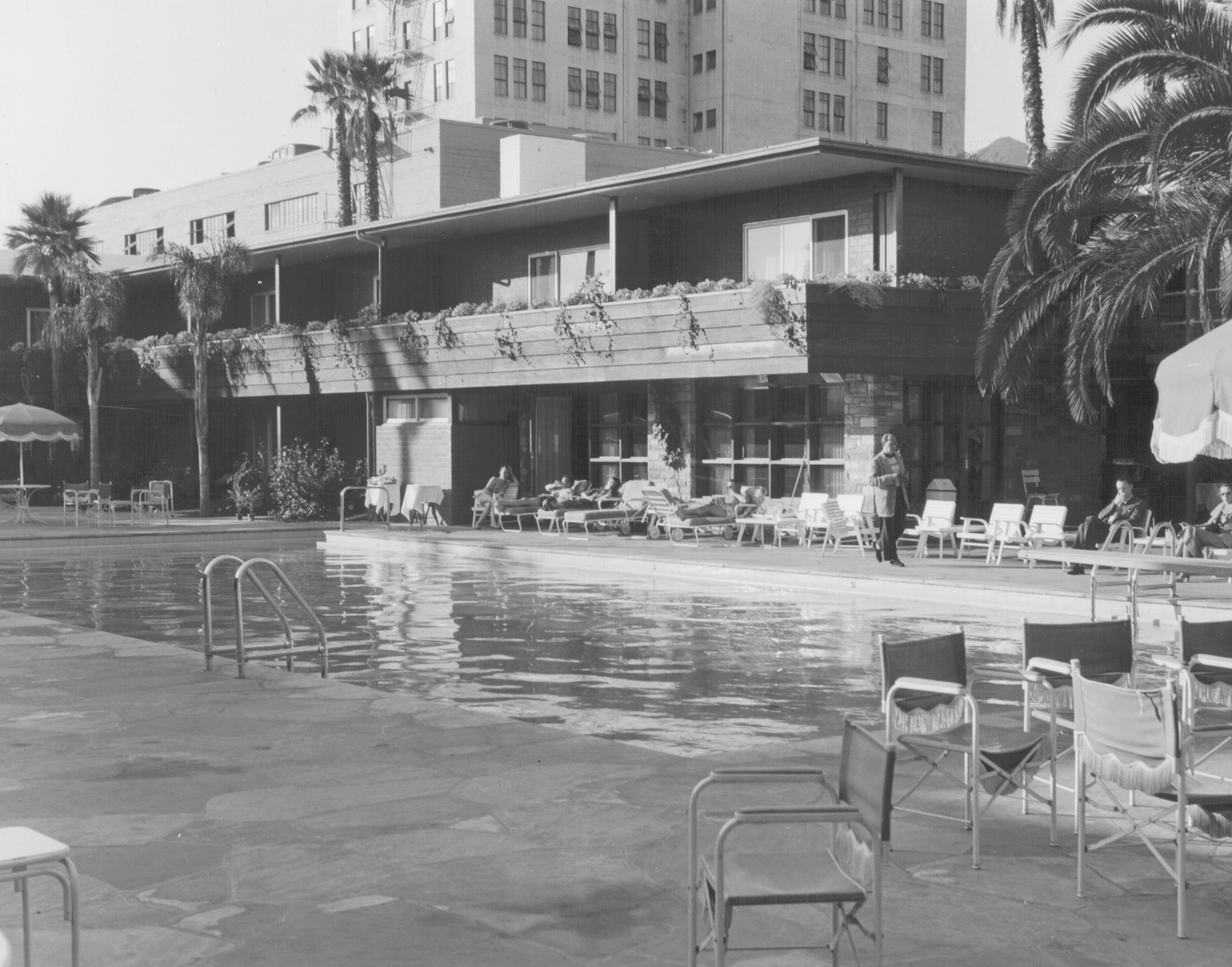 a pool with chairs and a building in the background