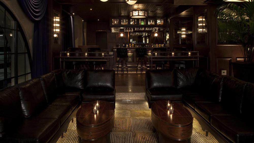 a dark room with leather couches and tables
