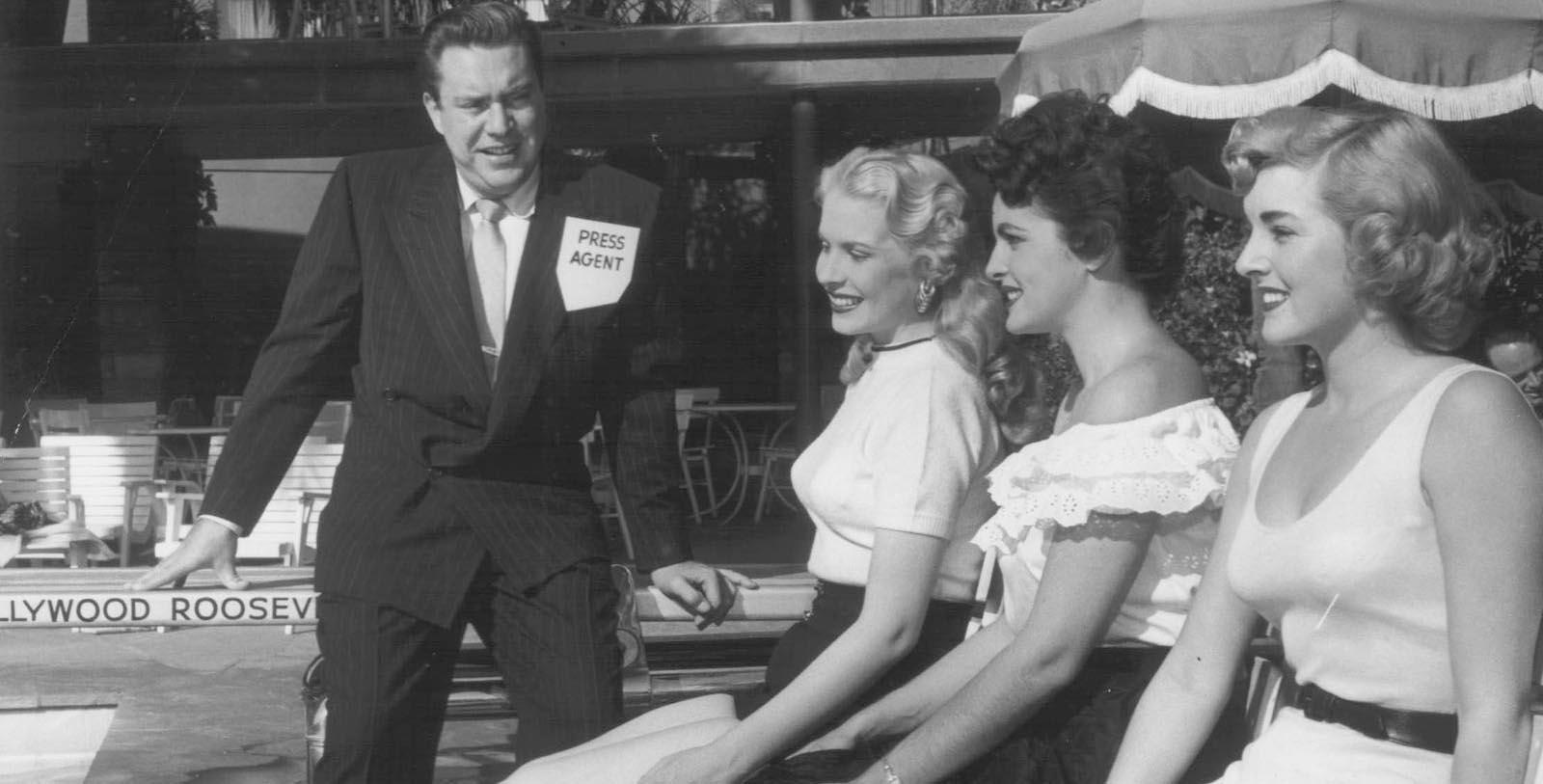 a man in a suit talking to a group of women