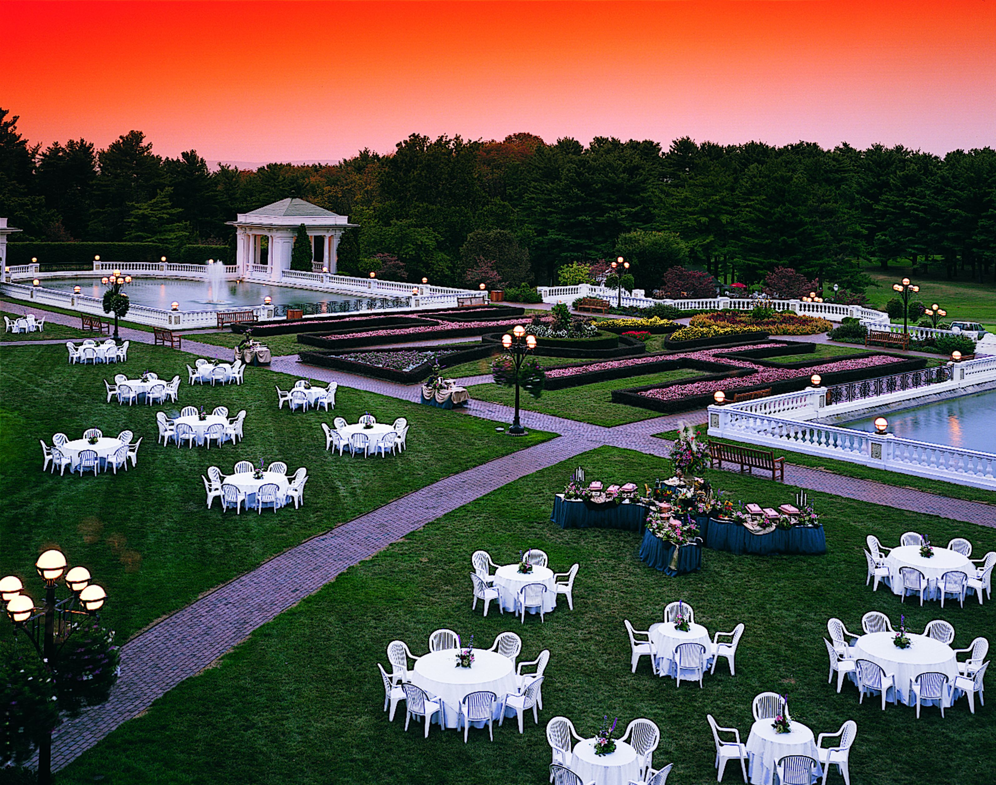 a large lawn with tables and chairs and a fountain