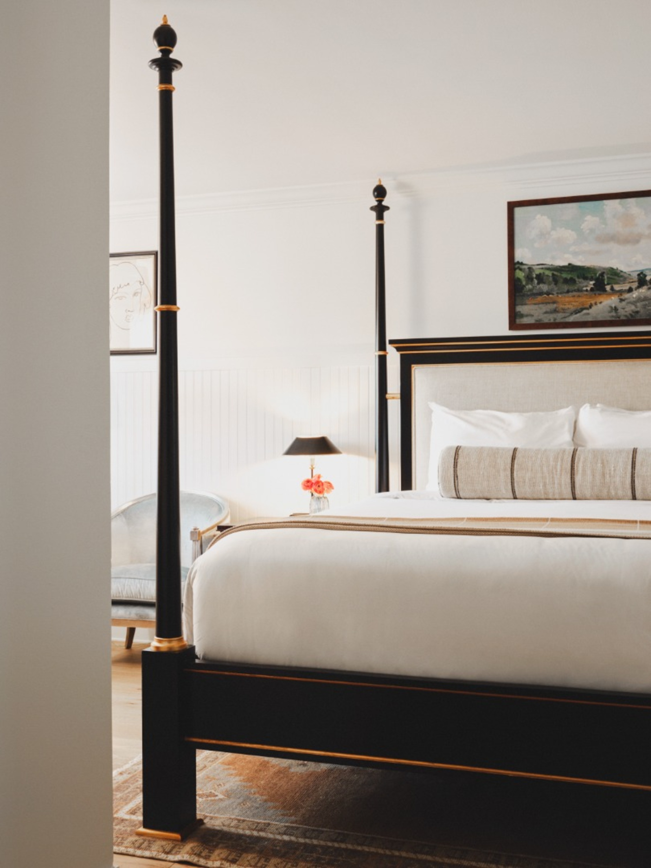 a bed with a black post and a painting above it