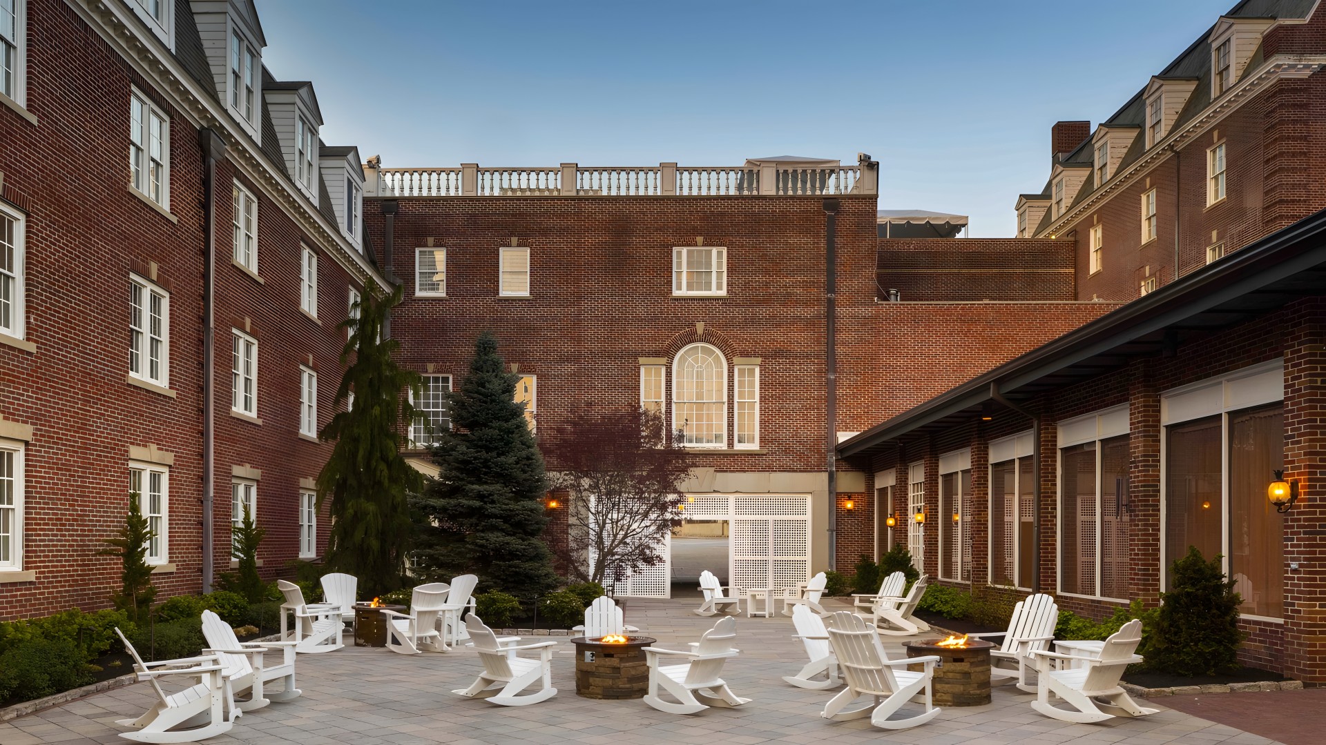 a courtyard with chairs and fire pit in front of a brick building