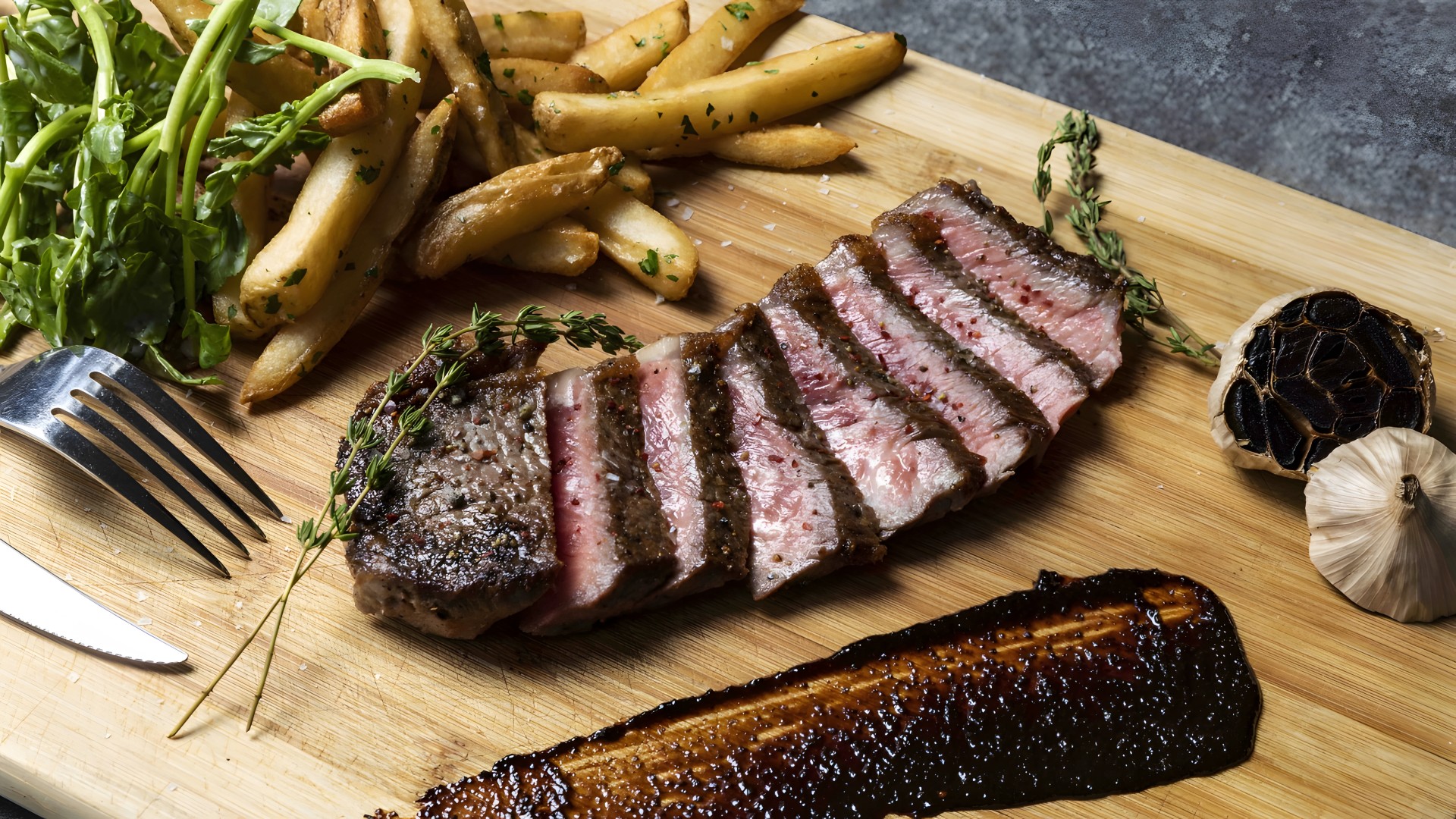 a steak and french fries on a wooden board