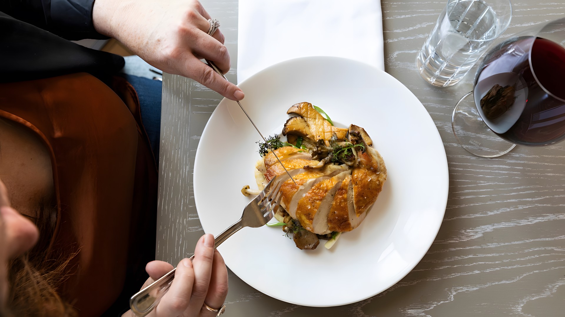 a person eating a piece of meat with a knife and fork