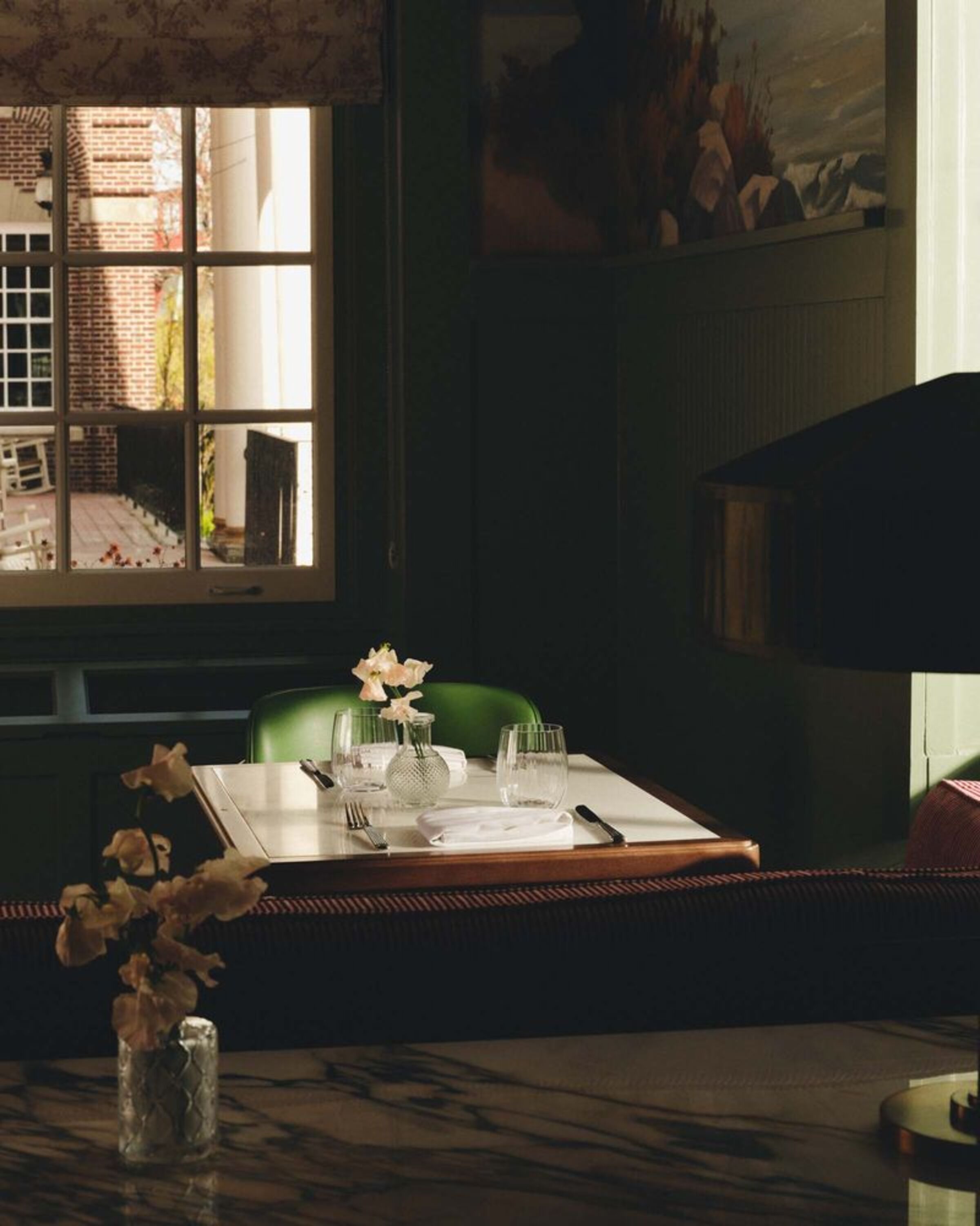 a table with a vase of flowers and a vase of flowers in front of a window