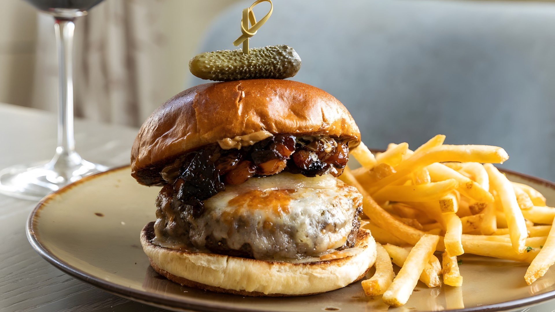a burger with a pickle on top and fries on a plate