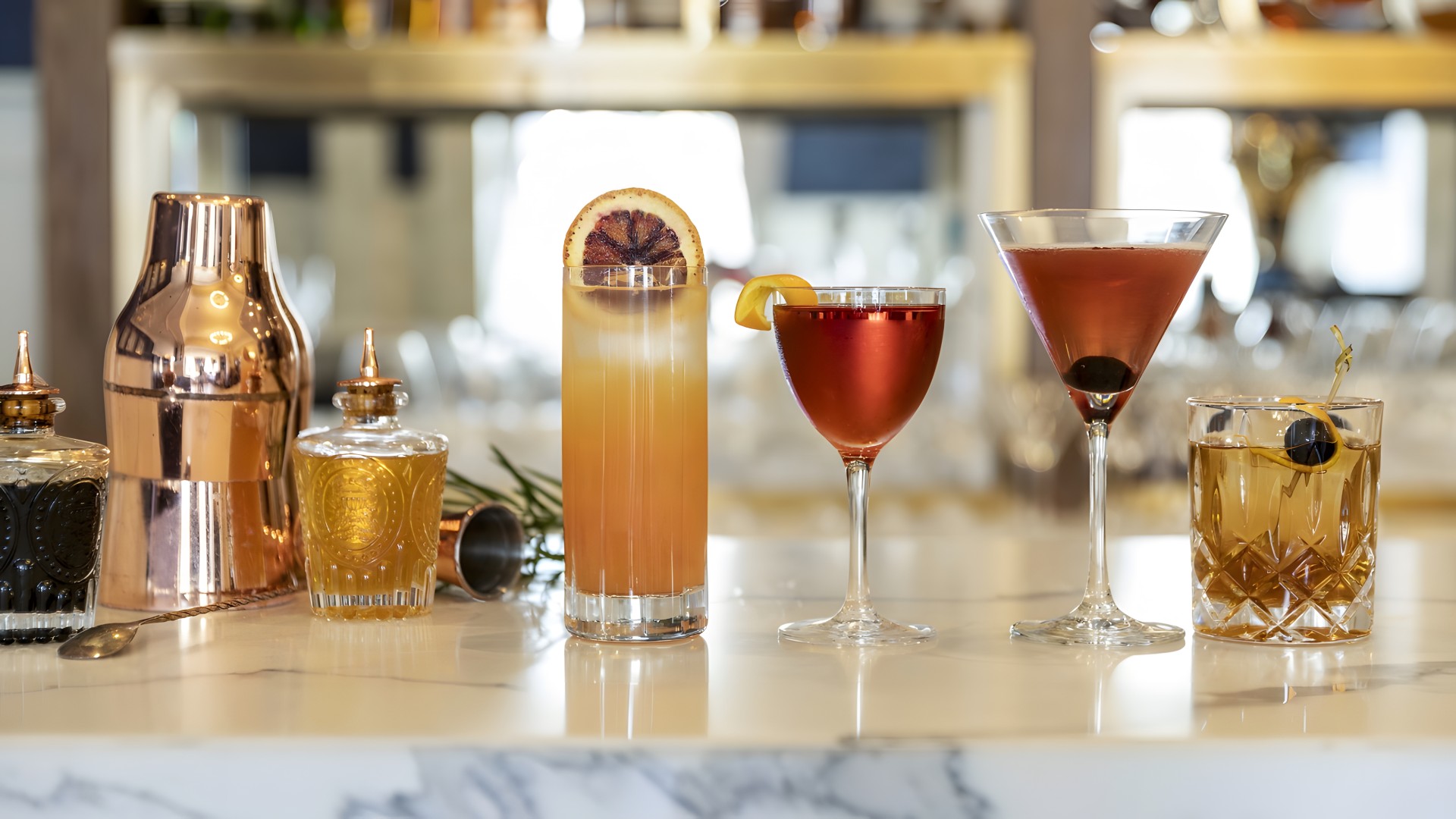 a group of glasses of different colored drinks on a counter