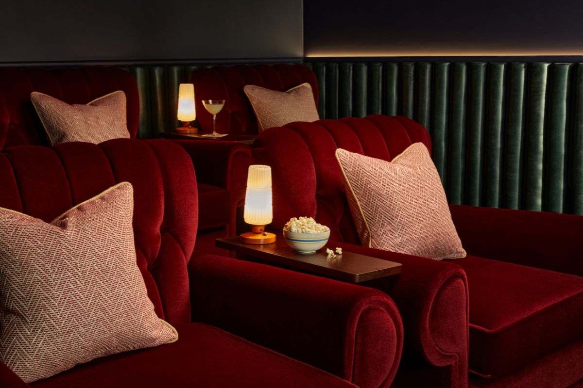a group of red couches with pillows and a bowl of popcorn on a table