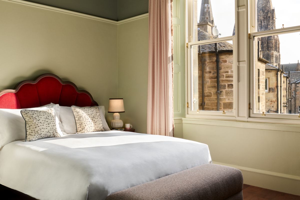 a bed with a red headboard and a lamp in a room with a window