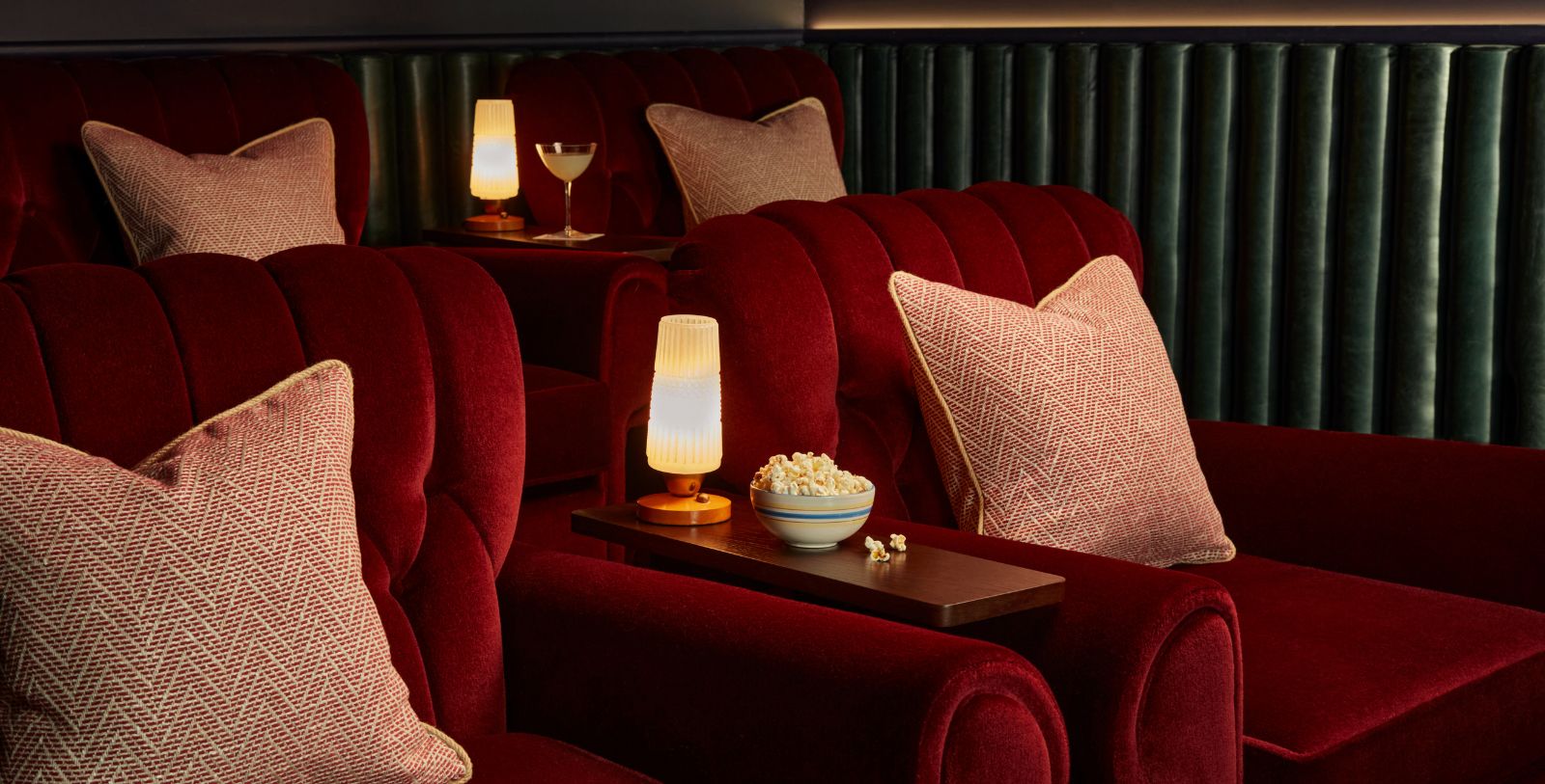 a red couches with a bowl of popcorn and a drink on a table