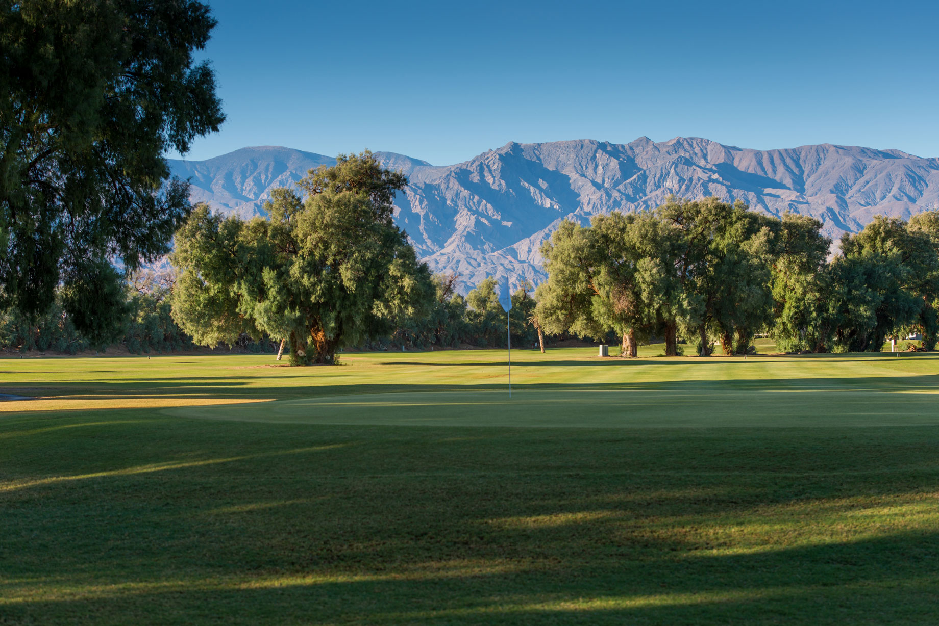a golf course with trees and mountains in the background