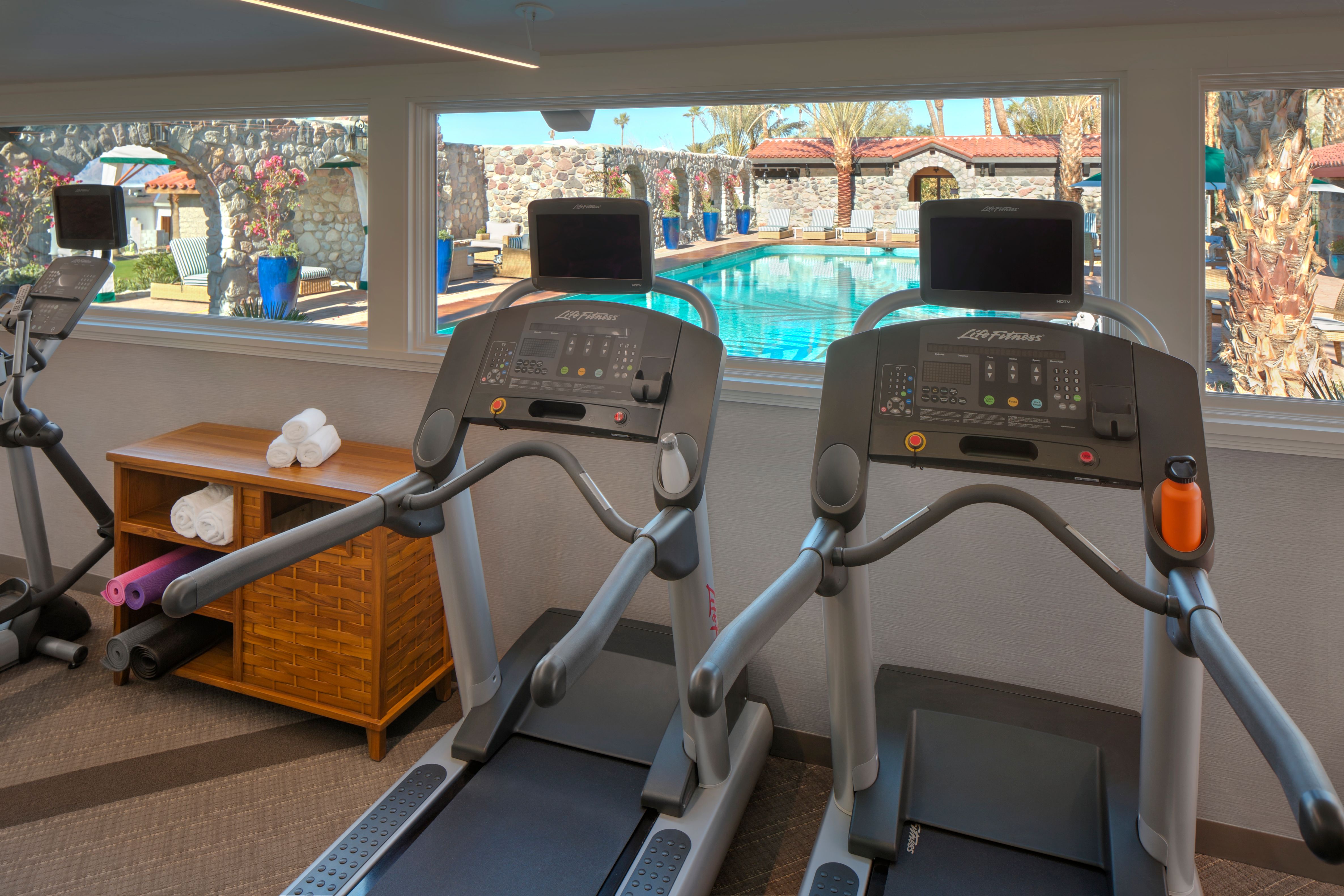 a gym with treadmills and a pool in the background