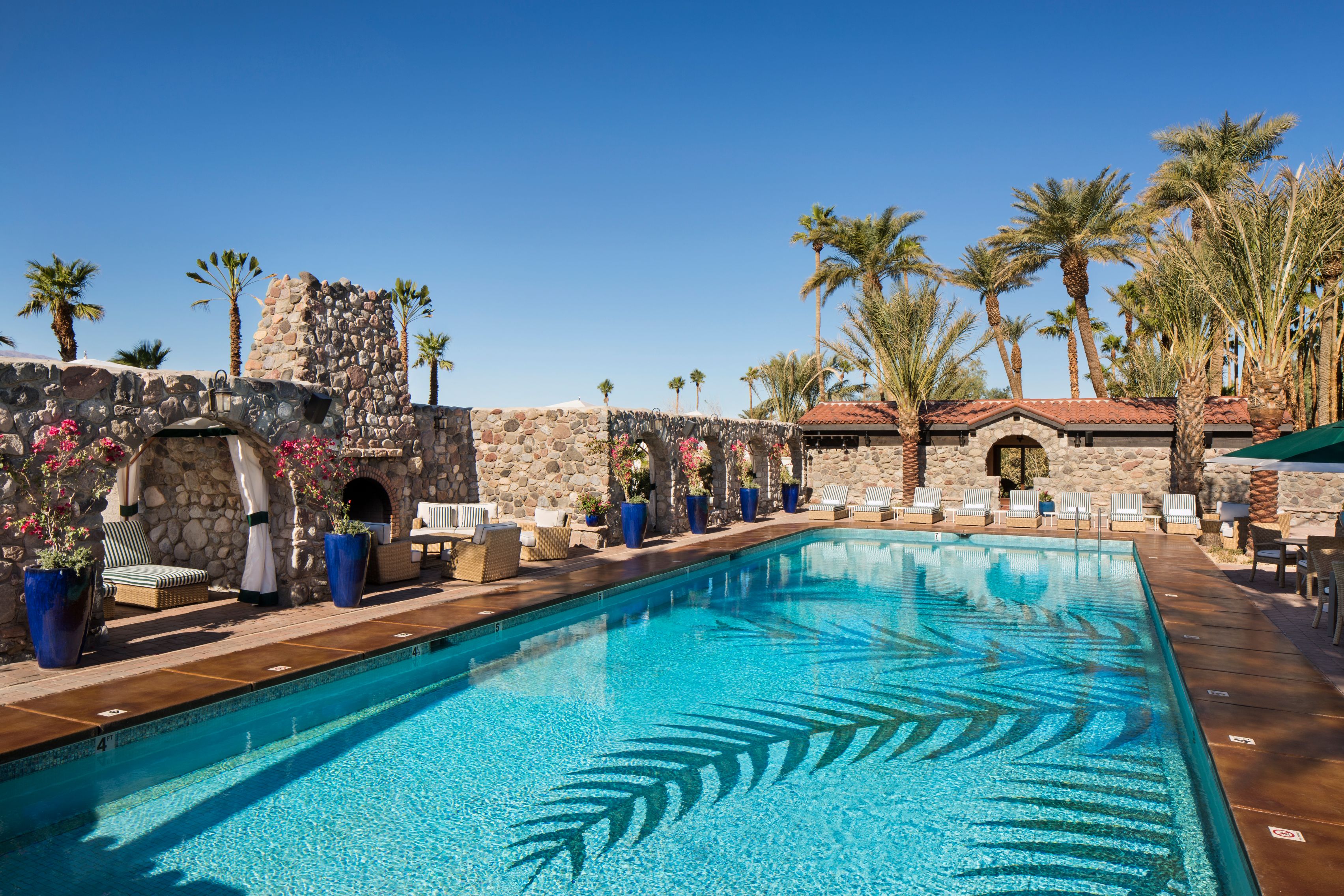 a swimming pool with palm trees and stone walls