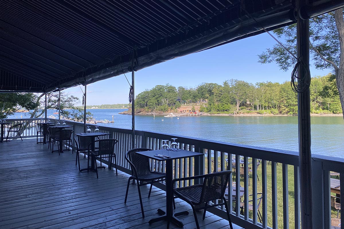 a deck with tables and chairs overlooking a body of water