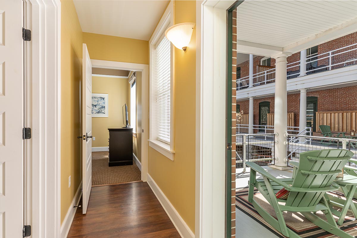 a hallway with a green chair and a wood floor