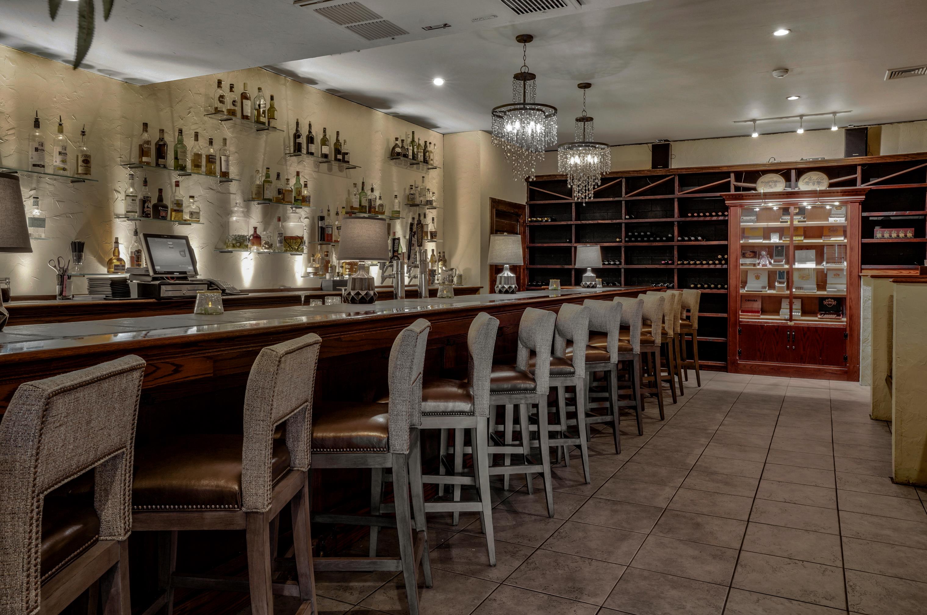 a bar with chairs and a chandelier