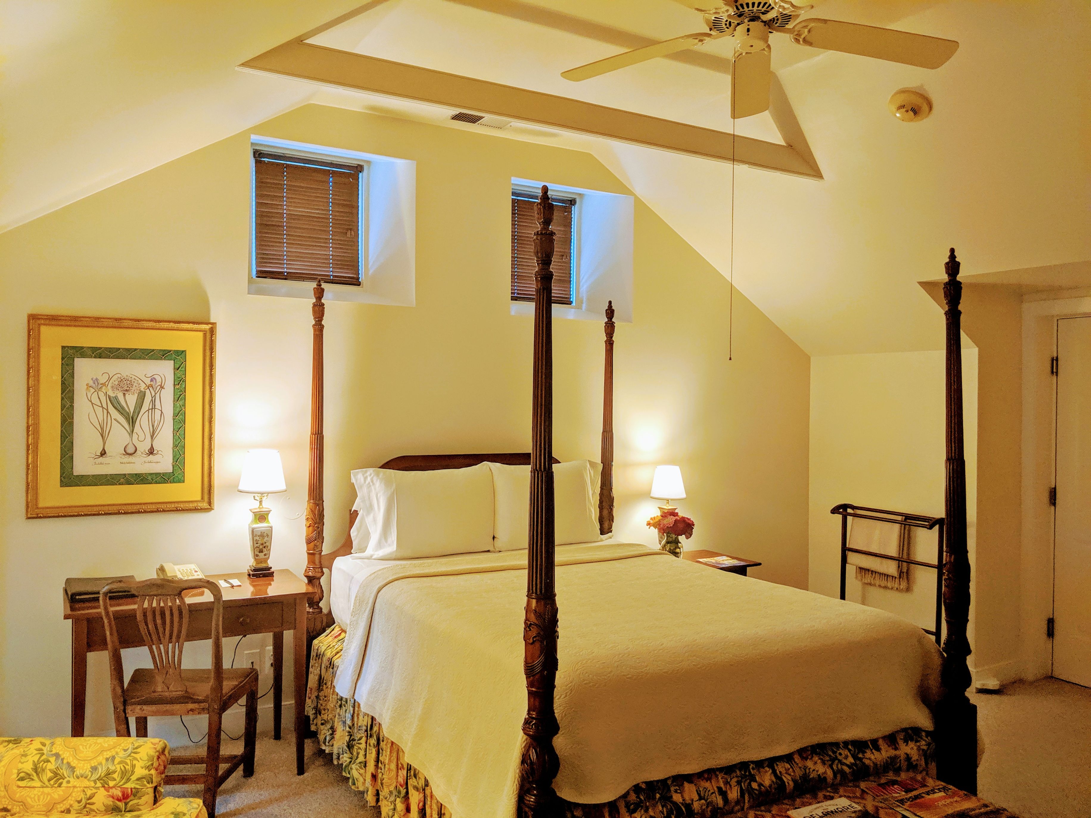 a bedroom with a four poster bed and a ceiling fan