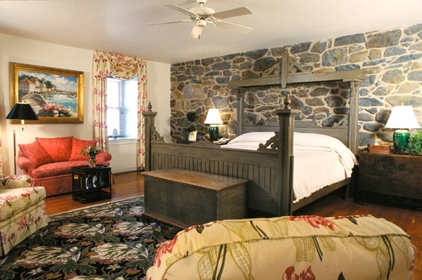 a bedroom with a stone wall and a bed