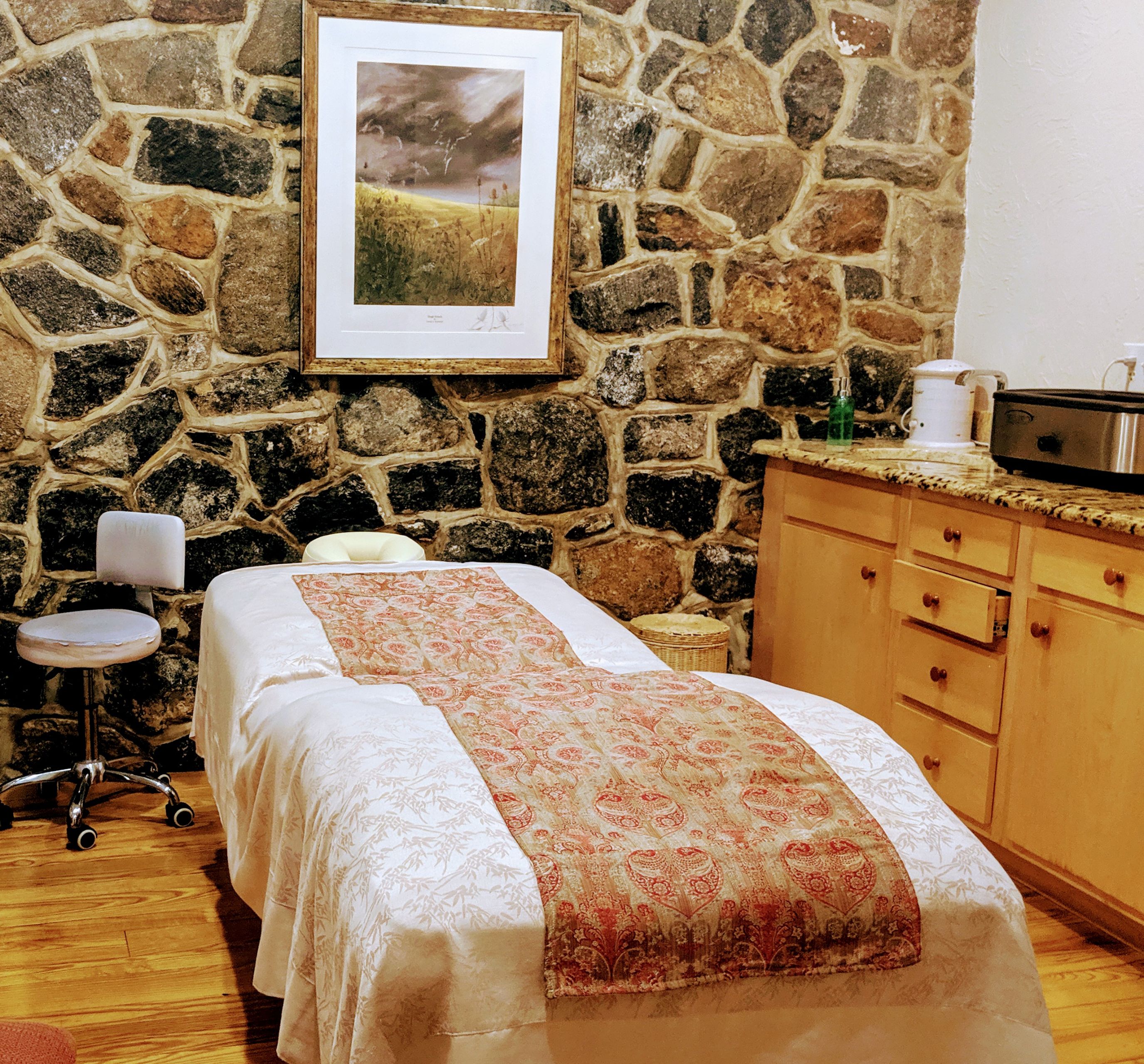 a bed in a room with a stone wall and a picture on the wall