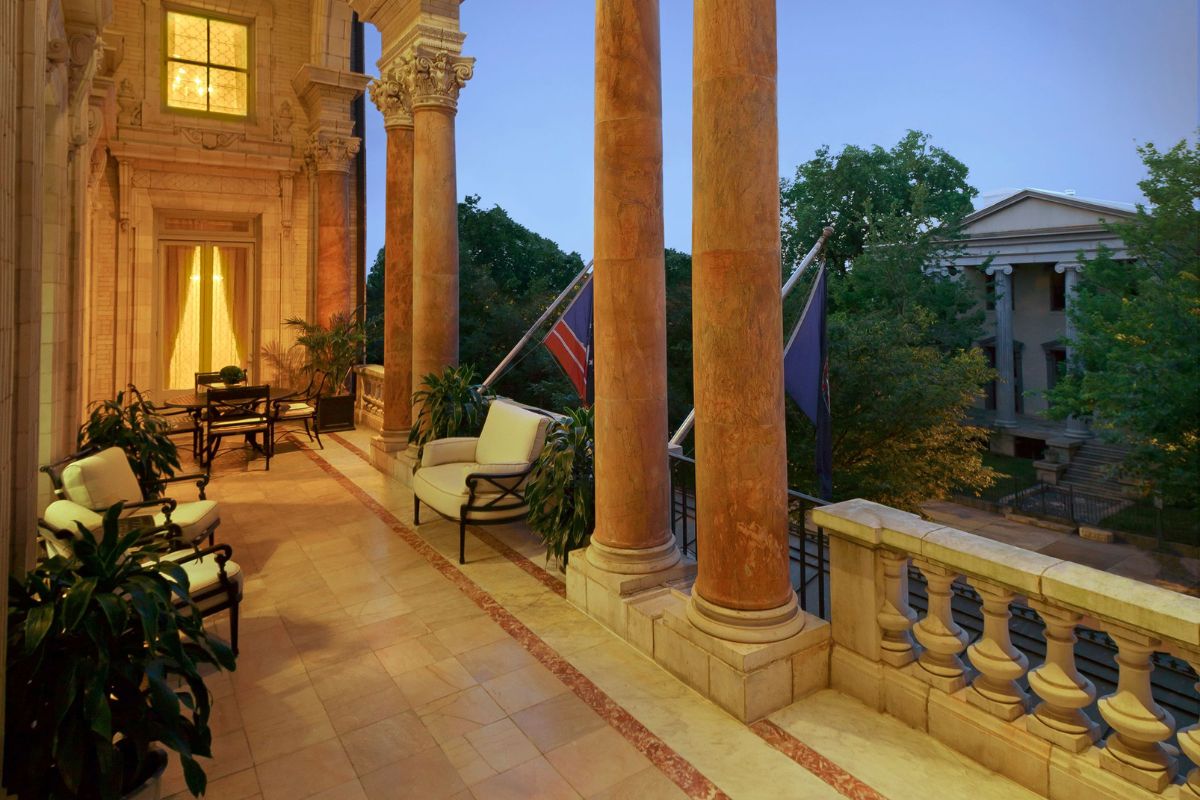 a patio with chairs and a balcony with columns